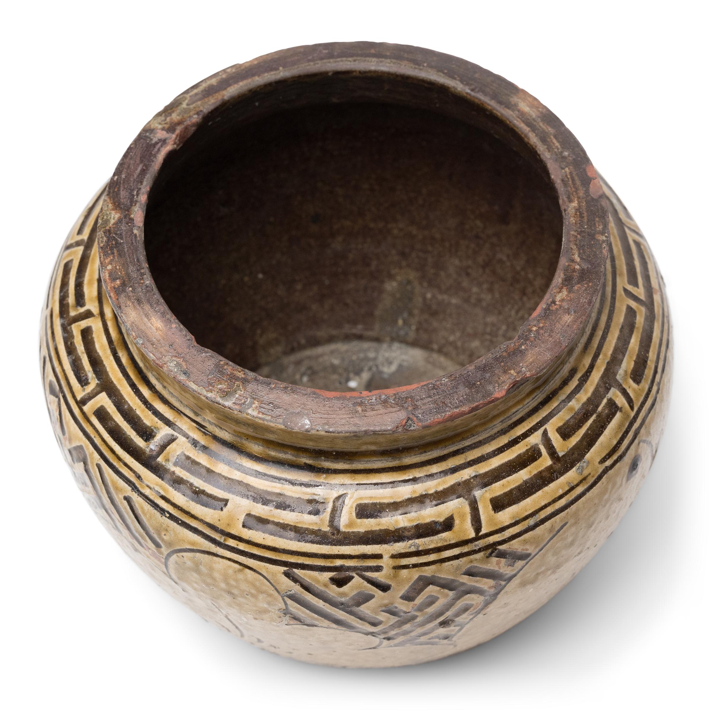 A late 19th-century Chinese kitchen vessel glazed inside and out for use as a food storage container or pickling pot. The terracotta jar has a squat shape with rounded shoulders, tapered sides and a widemouth neck. The surface is decorated with
