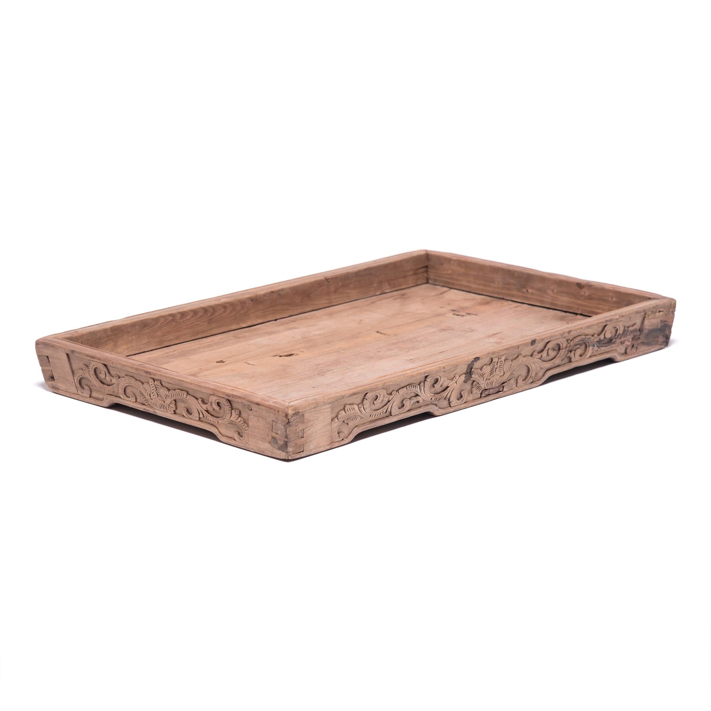 Finely carved floral and geometric motifs and a subtly recessed base give the simple lines of this century-old tray true provincial elegance. It has developed great character from years of serving tea, likely for friends and family gathered on