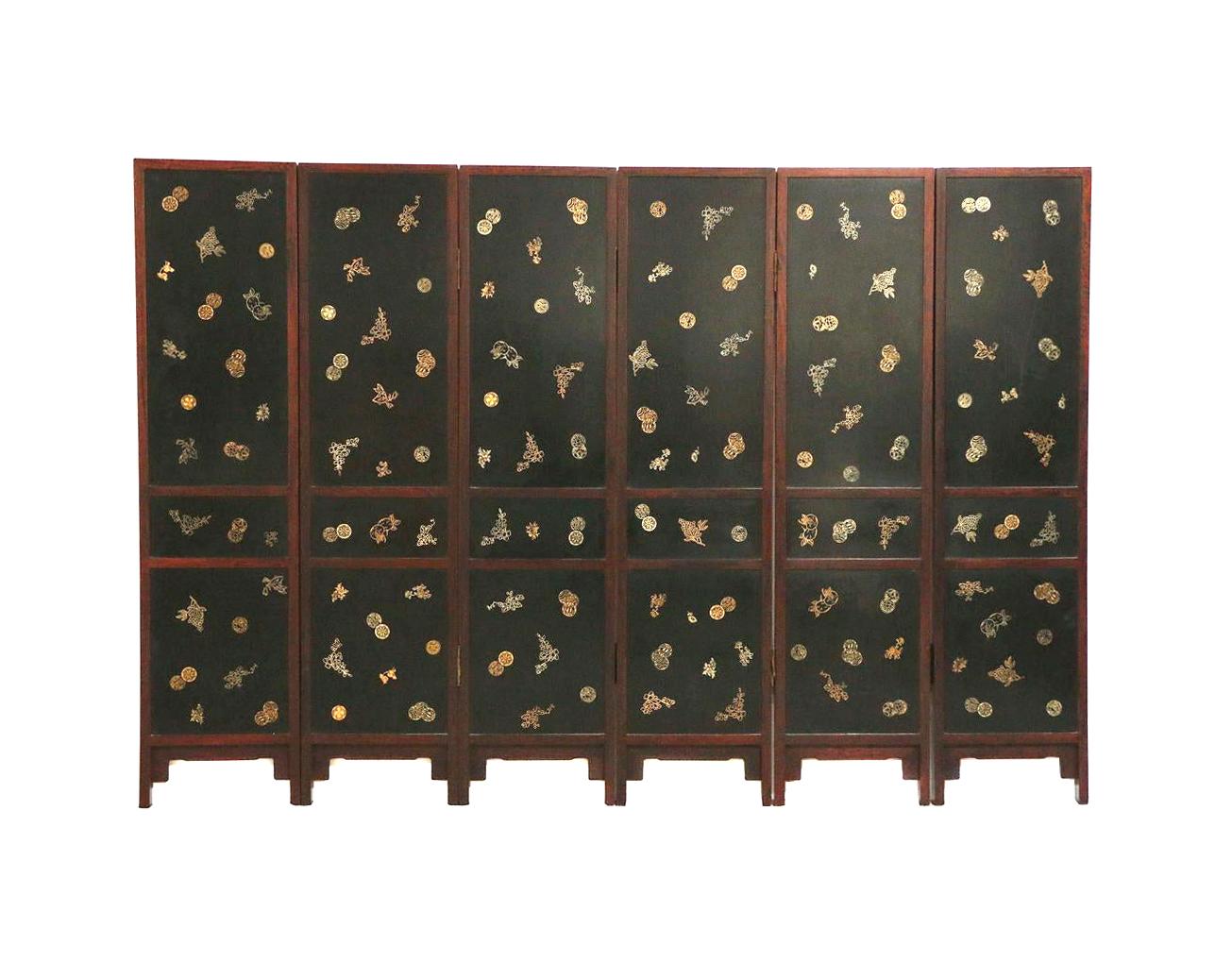 A six panel hinged folding floor screen from China circa end of the 19th- early 20th century. Each panel features three sections of black lacquered panels inlaid with a variety of objects carved from hard stones. The top features flowers in vases,