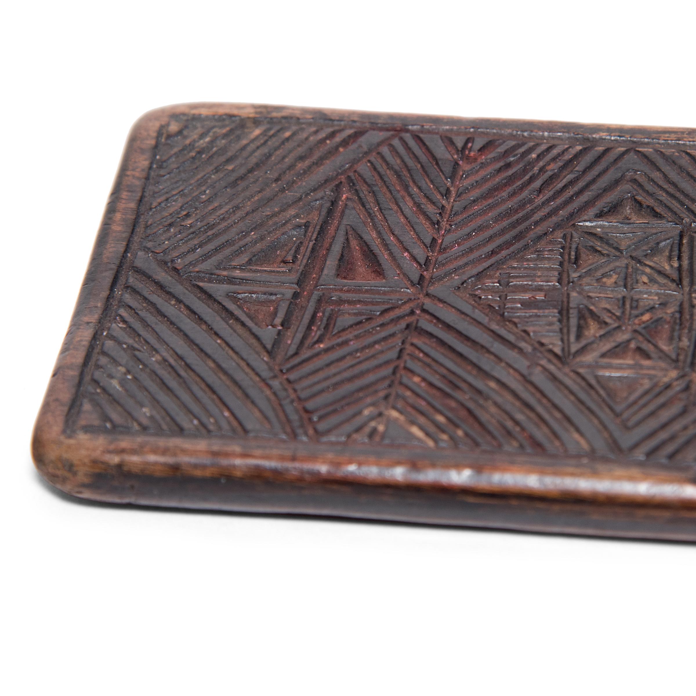 Dated to the 19th century, this flat wooden panel is curiously etched with geometric patterns and dense triangle-work. Its original use remains unknown, perhaps it was a divination tool, a traveling game board, or a weight to hold open a scroll. A