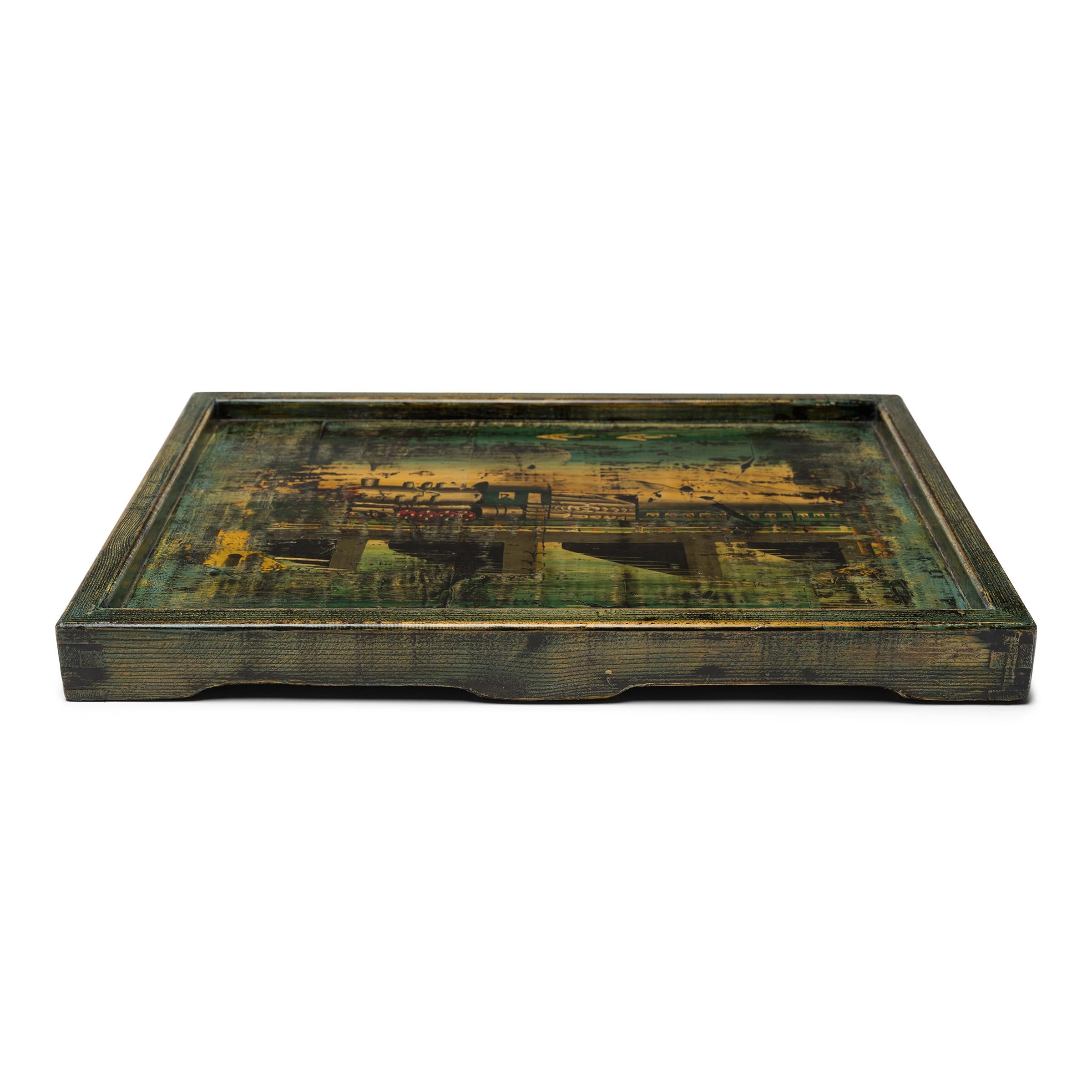 This lacquered serving tray is crafted with a hand-painted panel salvaged from a vintage Chinese cabinet. Selected for its charming folk art decoration, the found panel is painted with a steam locomotive passing over a river in a scenic mountain