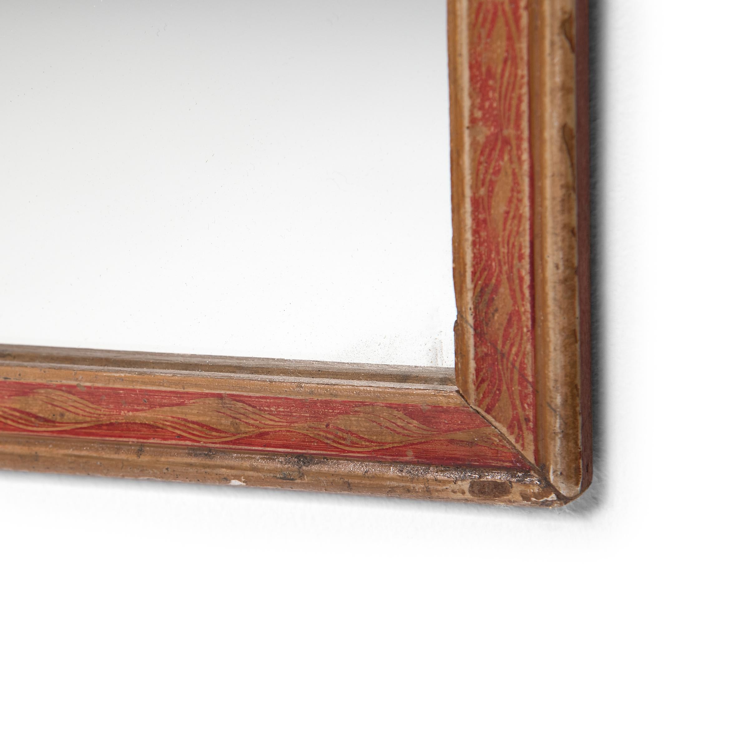 Der bemalte Rahmen dieses Wandspiegels grenzte ursprünglich an eine Hinterglasmalerei, eine traditionelle Kunst, bei der der Künstler ein Bild spiegelverkehrt malen musste, beginnend mit den Details. Der Rahmen, der nun einen neuen Spiegel