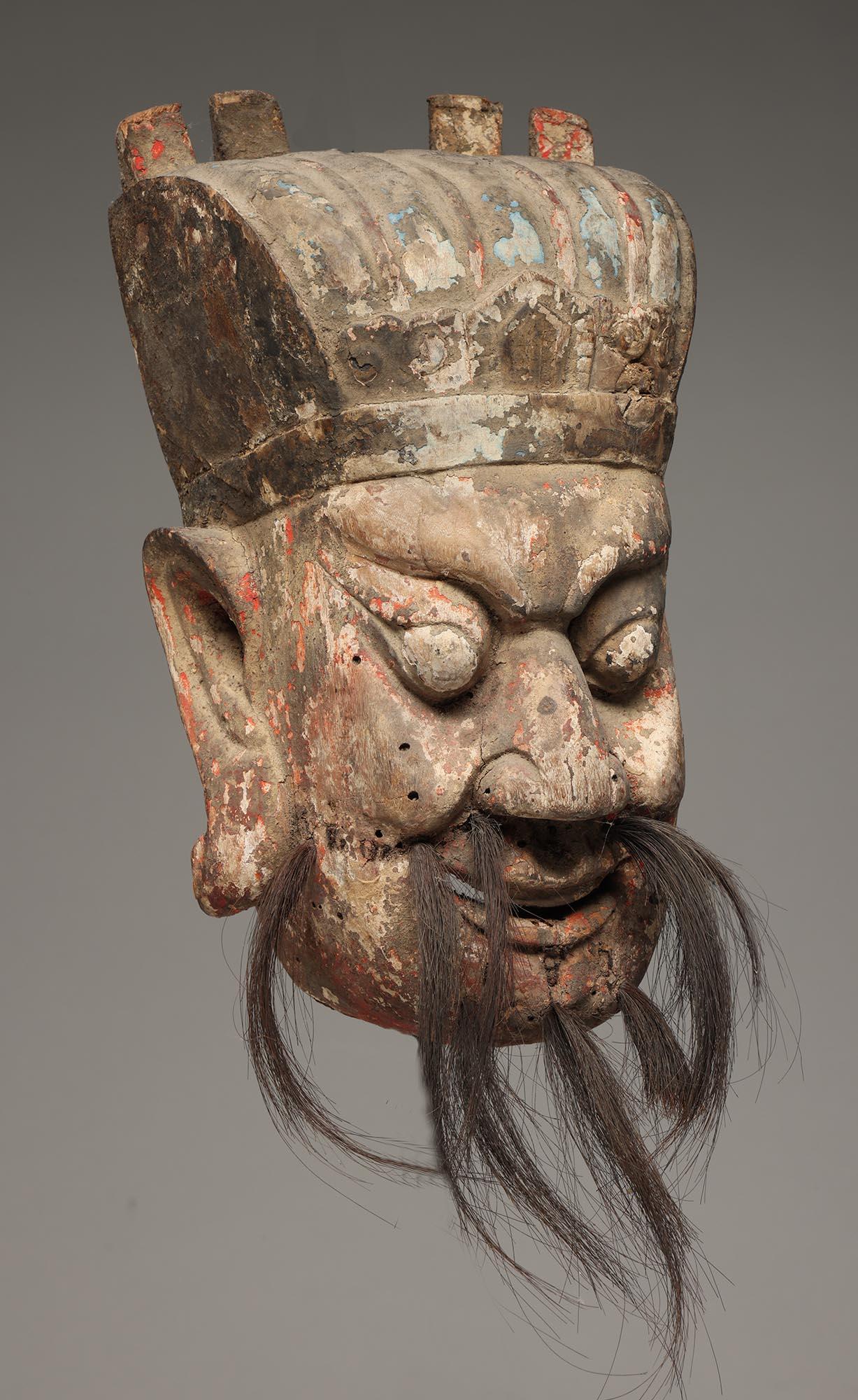 Masque de danse en bois sculpté de Chine avec expression ouverte, moustache et barbe attachées, grandes oreilles. Traces de nombreuses couches de peinture, notamment de pigments rouges, bleus, noirs et blancs.

Ex- collection privée en Californie,