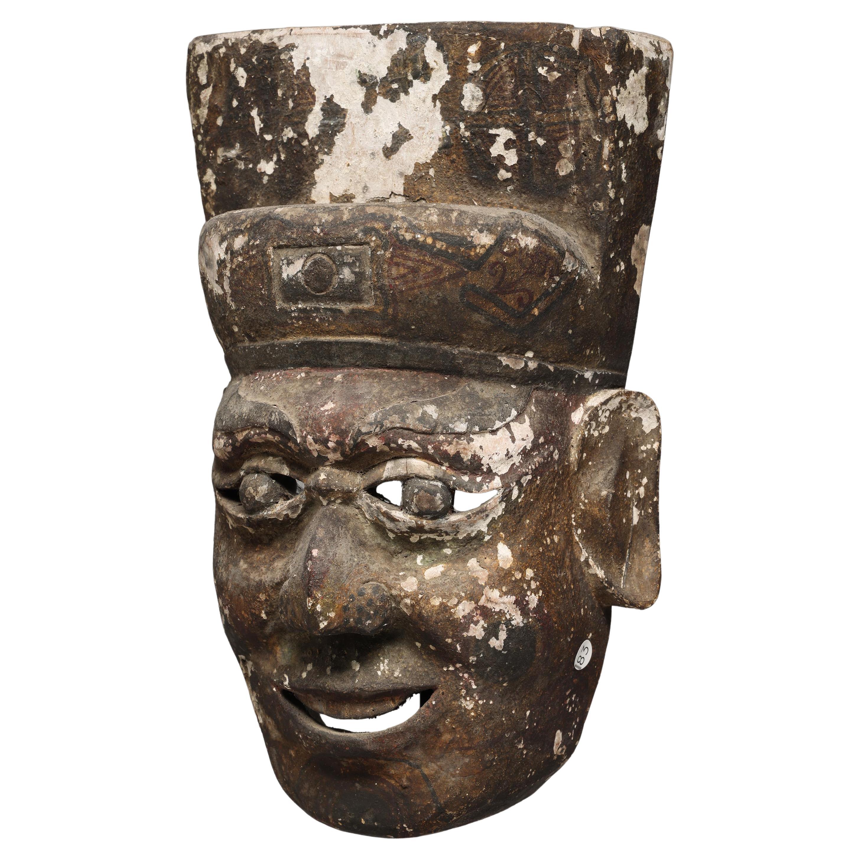 Maschera folcloristica cinese in legno con espressione sorridente e tracce di pittura dalla Cina