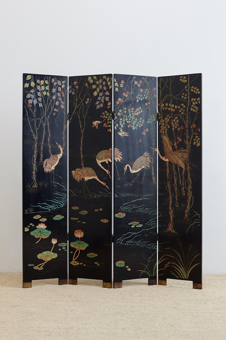 Gorgeous Chinese four-panel Coromandel screen featuring red-crowned cranes among trees and lotus blossoms. Dramatic color over a black lacquer background. Two-sided with the reverse having minimal decoration of bamboo, flower blossoms, and birds.