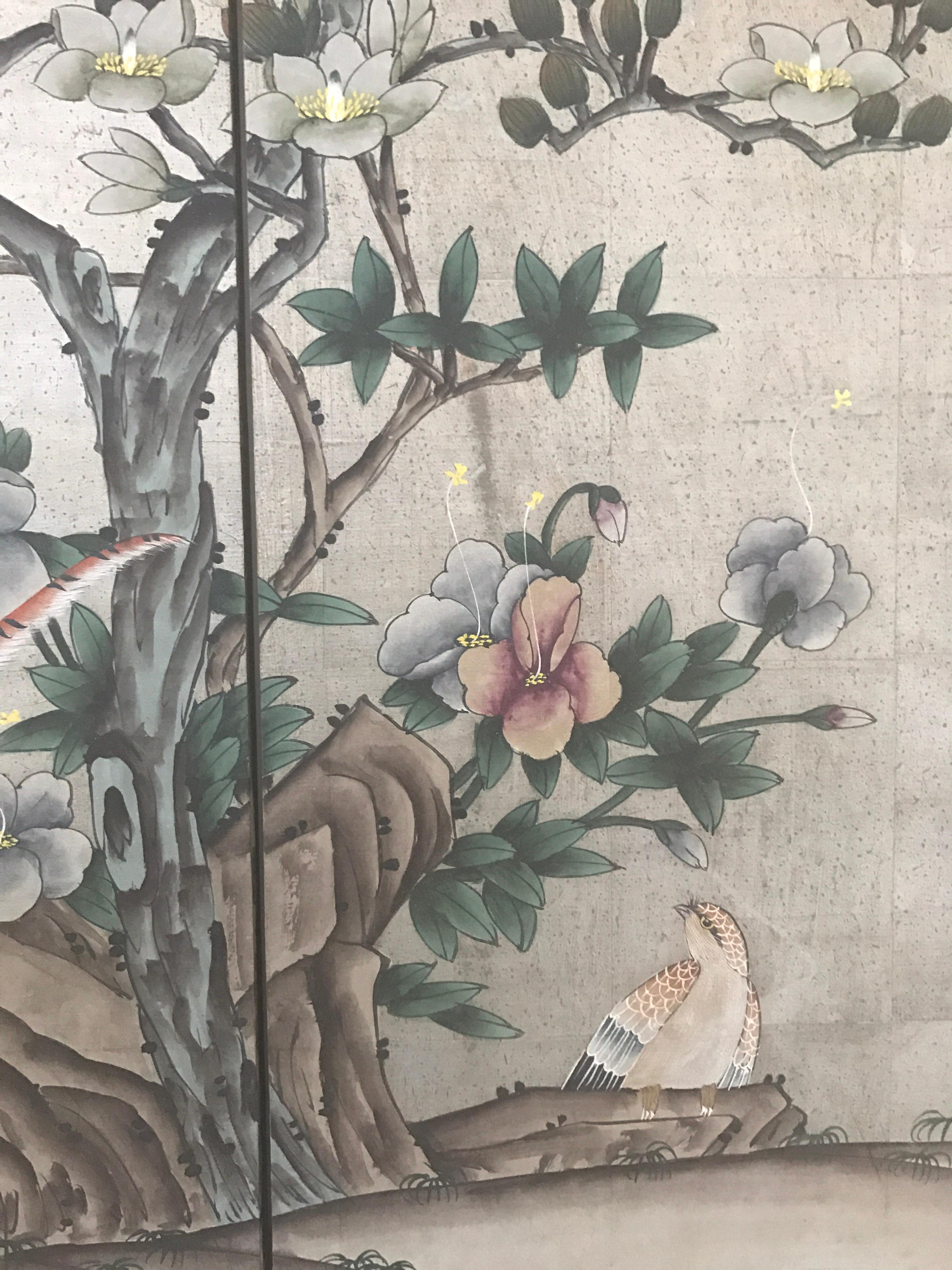 Elegant chinoiserie style four-panel screen decorated with hand painted scenery of trees, flowers and birds on a silver leaf background. Has brass hardware and is ready to hang.