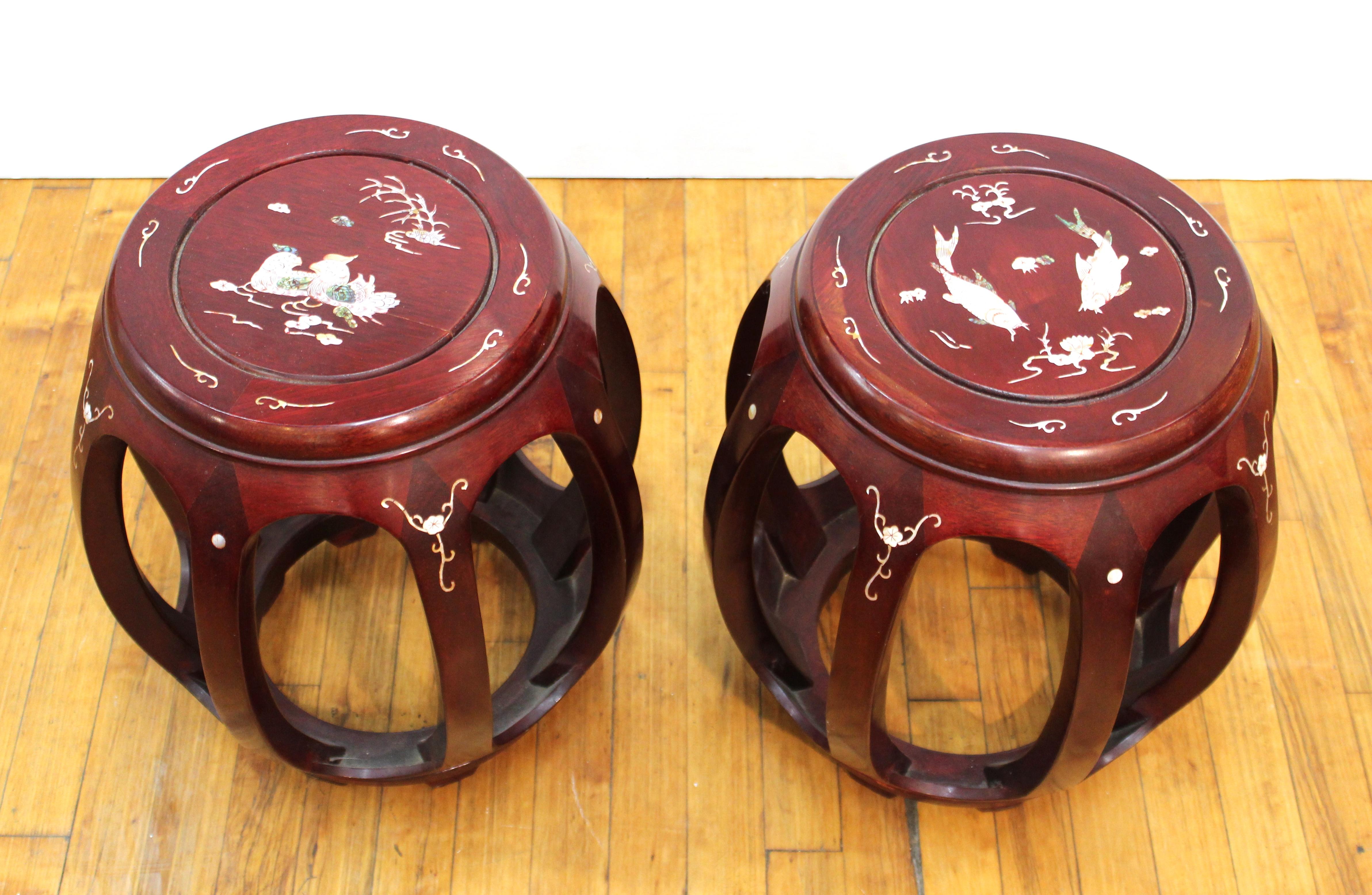 Chinese pair of carved wood garden seats with mother of pearl inlay of decorative birds and fish. The pair is in great vintage condition with age-appropriate wear and use.