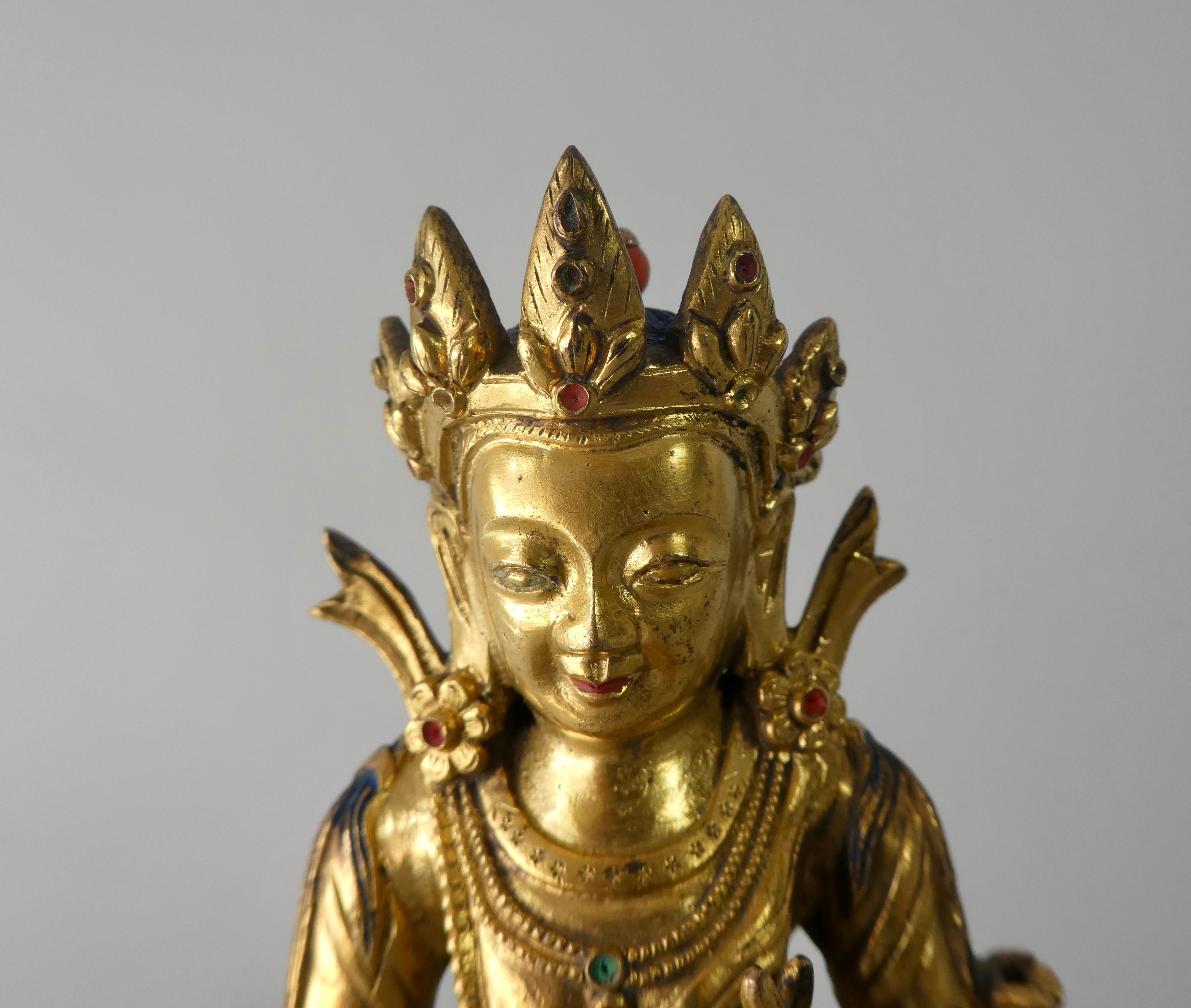 A fine Chinese gilt bronze figure, late 17th-early 18th century. Cast as green tara seated in lalitasana, and her right foot resting upon a lotus blossom. Her hands in varada, and vitarka mudra. She is dressed in a dhoti, with engraved scrollwork to