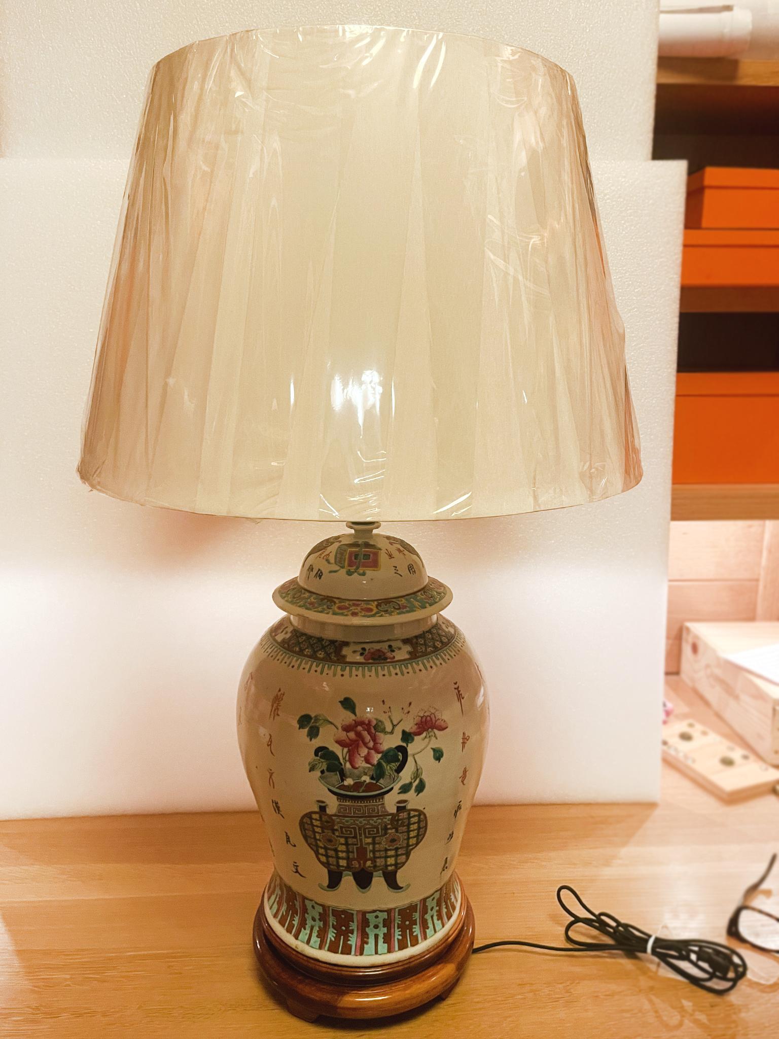 This Mid-20th Century ginger jar urn lamp from China has a beautiful ceramic with a pale gray glaze. Delicately painted floral motifs adorn the surface along with colorful geometric borders and writing. The base is wood with a warm red-brown tint.
