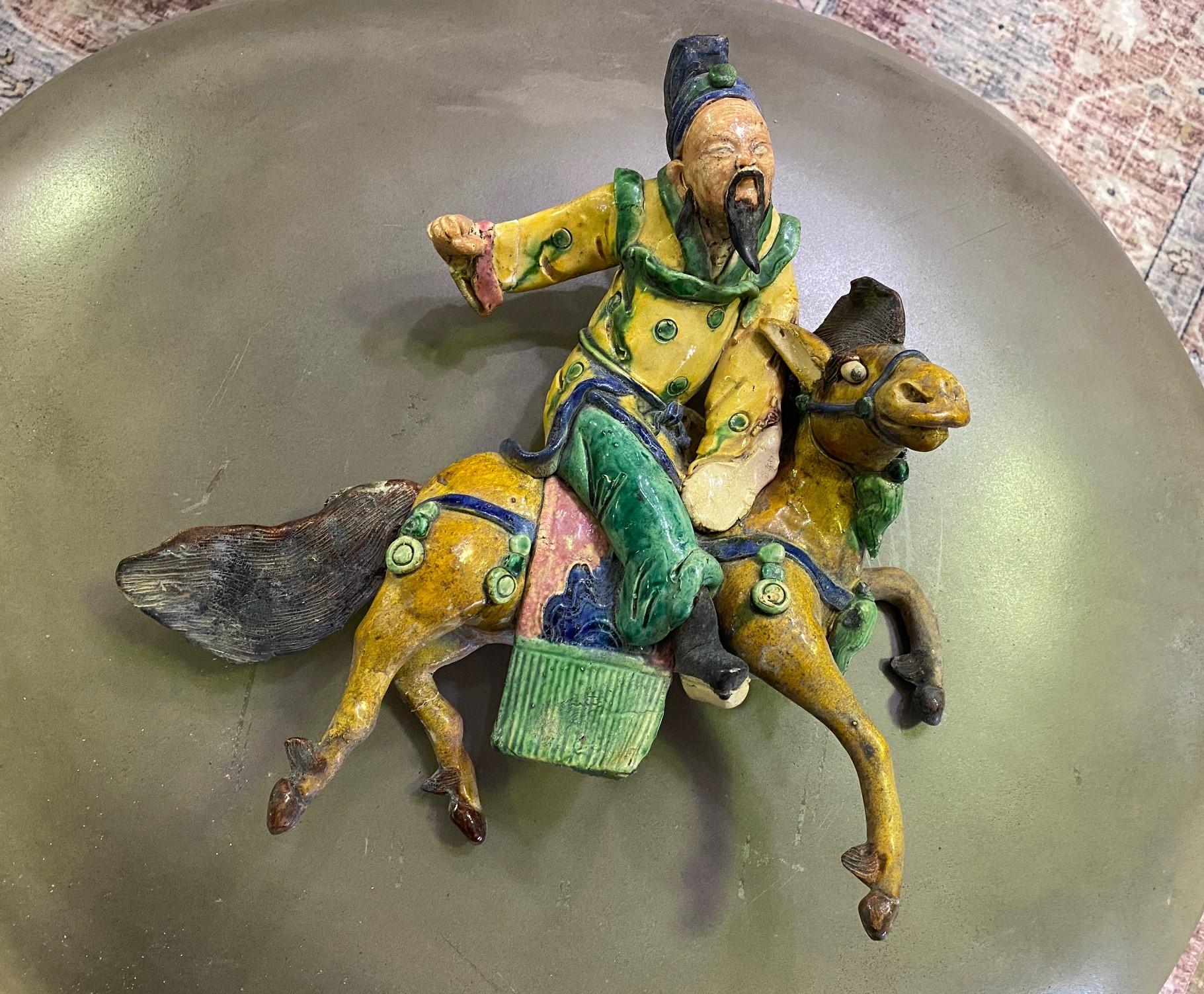 A fantastic piece. Wonderfully glazed and colored work of a seated man with brightly colored robes riding a mythical galloping horse. 

We believe this is Qing Dynasty (1644-1912) but this is not our area of expertise so are listing it simply as