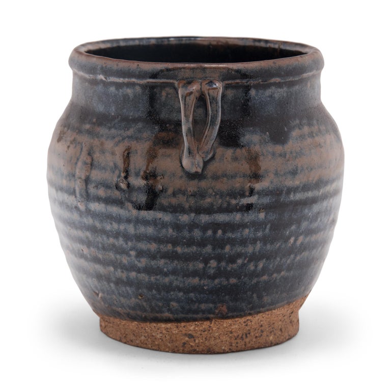 A dark glaze drips down the sides of this petite storage jar, pooling between subtle ridges to create a pattern of light and dark across the vessel. Crafted in the late 19th century, the wide-mouth jar was once used to store food in a Qing-dynasty