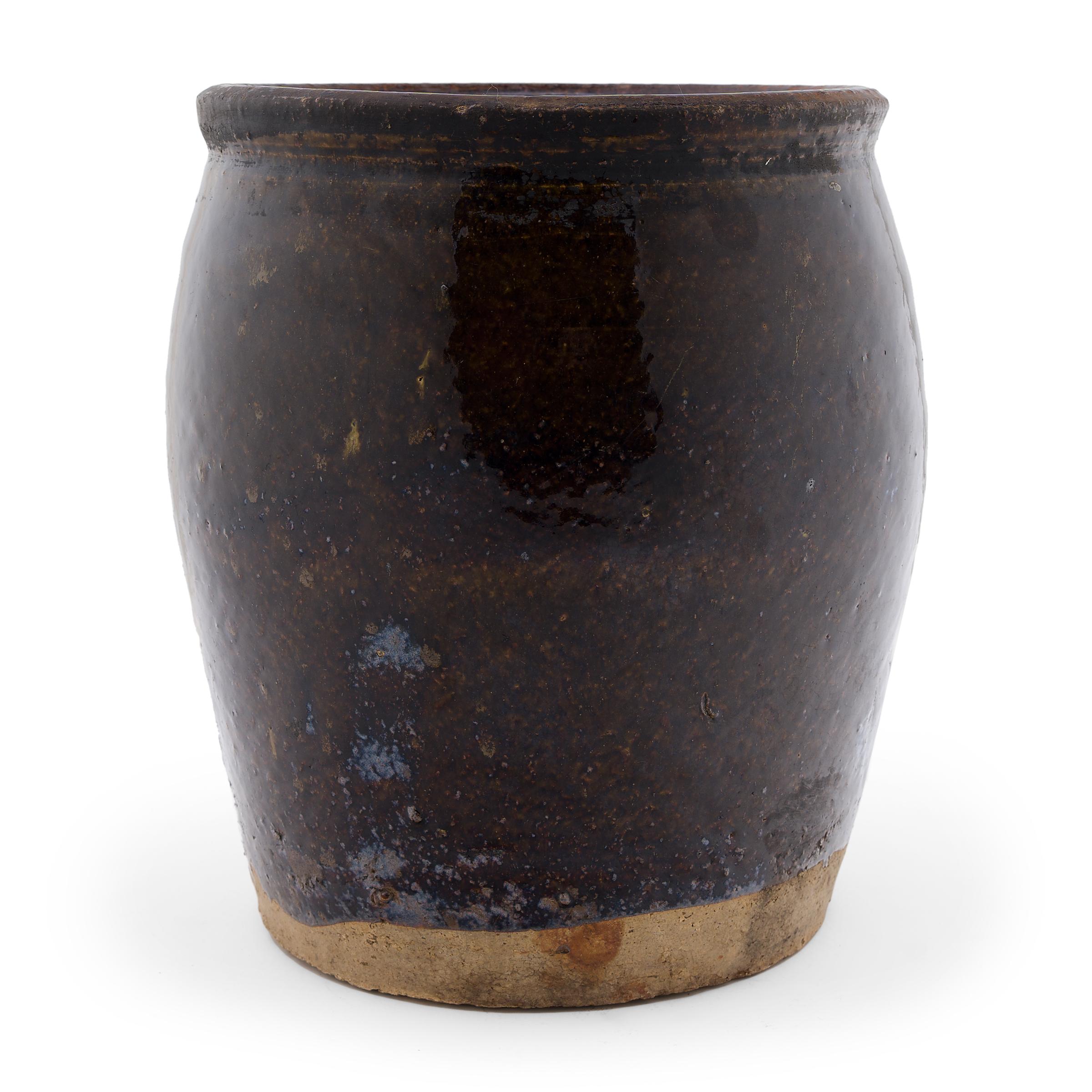 Coated inside and out with a rich, dark brown glaze, this 19th-century jar was originally used for fermenting foods and condiments in a provincial Chinese kitchen. The wide-mouth jar has a slightly tapered form with rounded shoulders and a flared