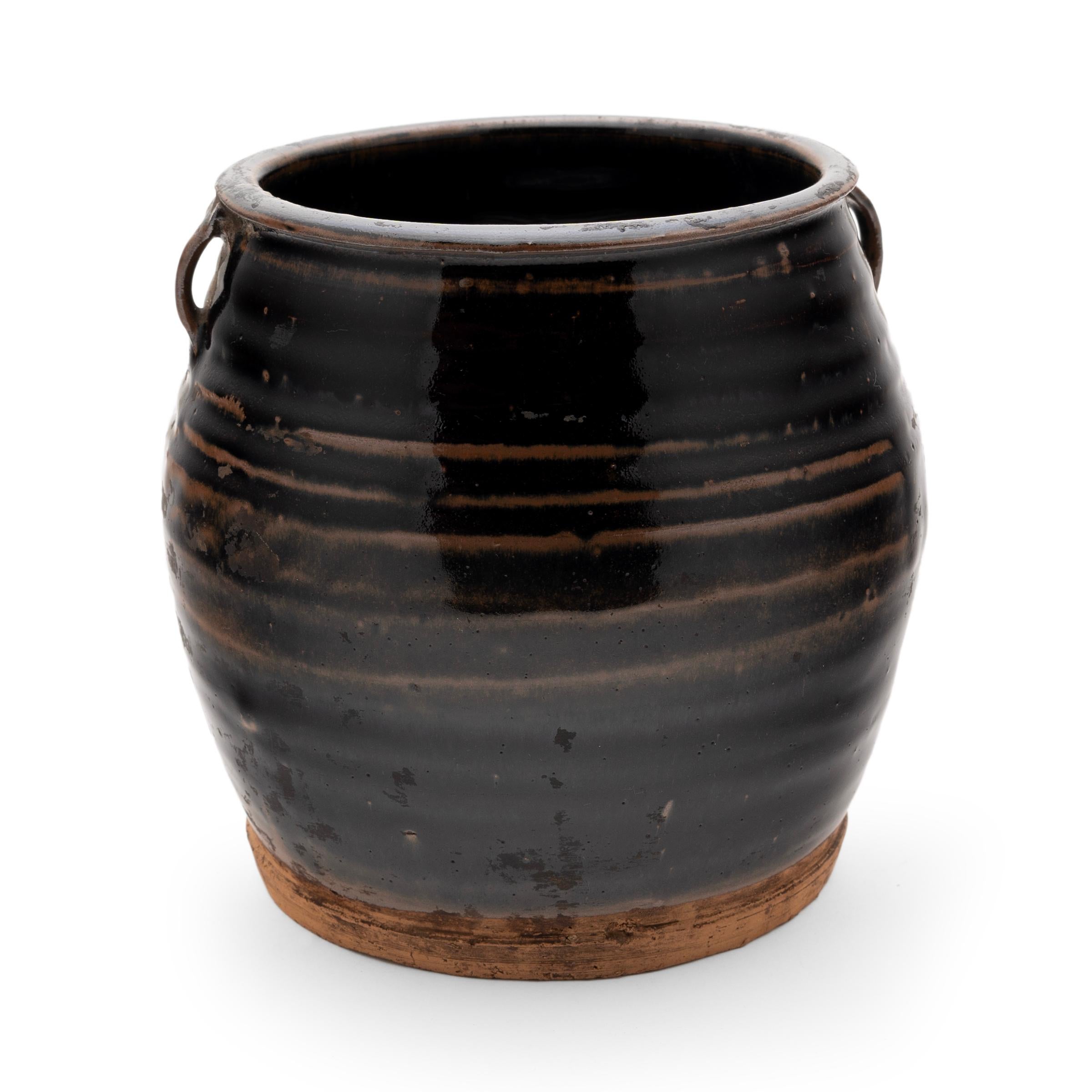 A thin black glaze coats the stout body of this early 20th-century terra cotta kitchen jar. As evidenced by the glazed interior, this wide-mouth jar was once used daily in a provincial Chinese kitchen for fermenting foods and condiments. The kitchen