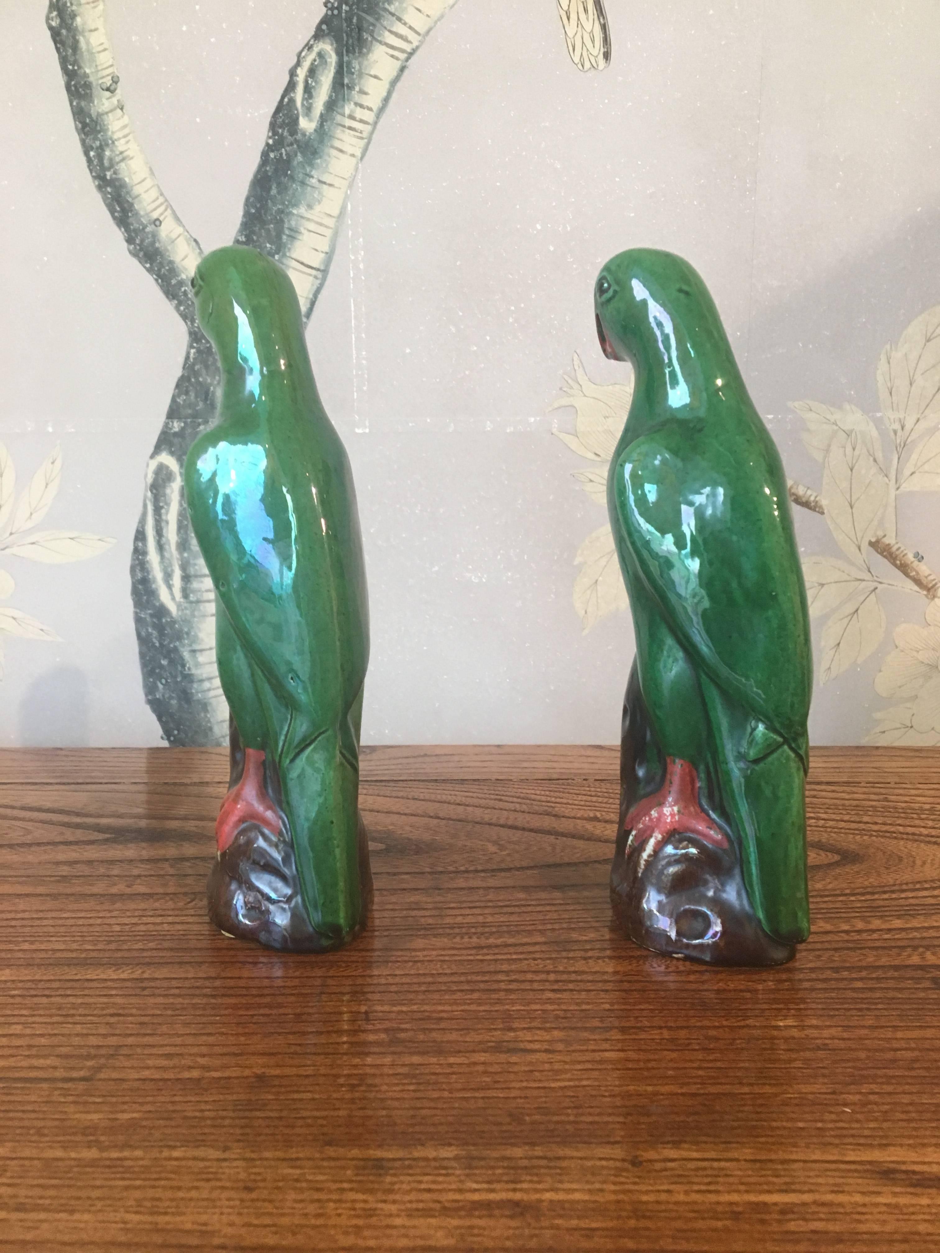 A pair of green early 20th century Chinese glazed parrots.