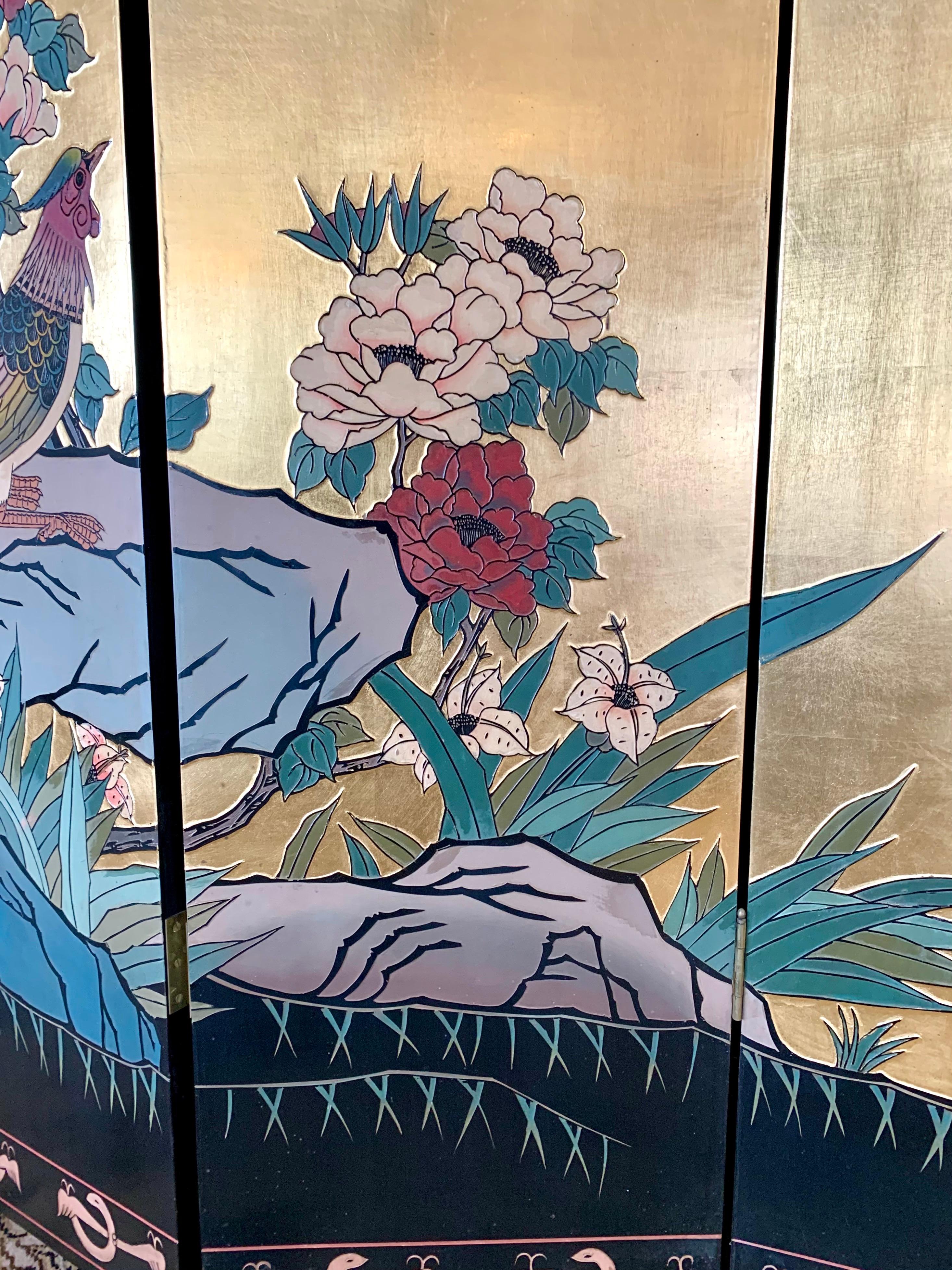 Exceptional detail throughout this vintage four-panel Asian chinoiserie folding screen/room divider. Front of screen features a raised painted landscape of trees, birds and flowers on a gold leaf background. Back of screen is black lacquer with lily