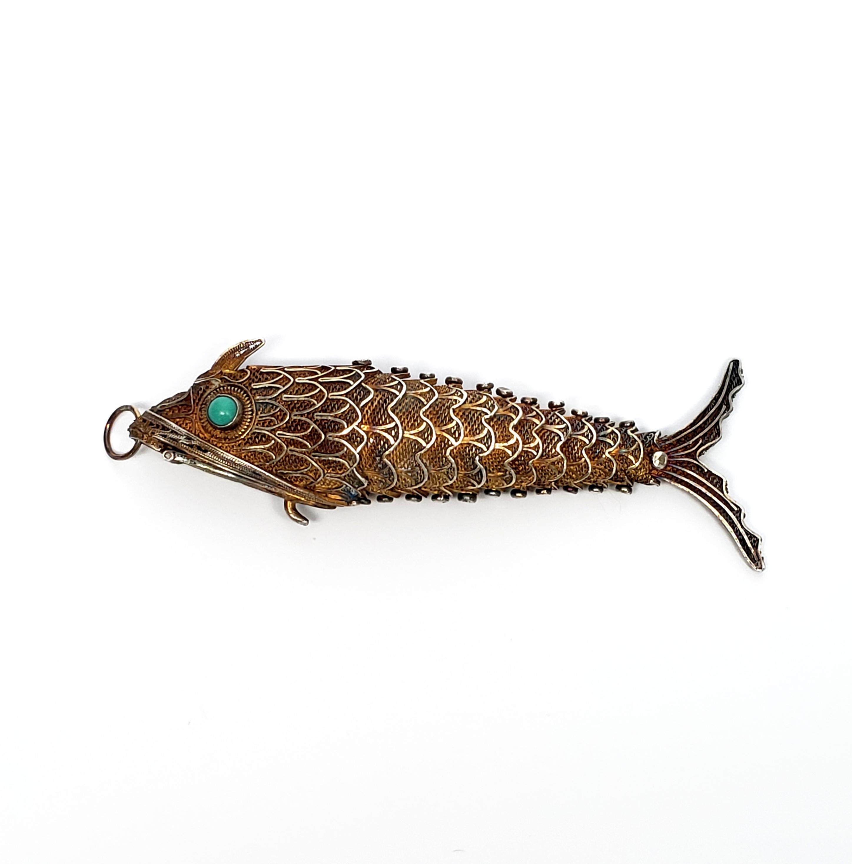 Antique gold vermeil over silver articulating fish pendant with turquoise eyes.

Large fish pendant, the mouth opens to hold pills or a scent sponge. Bezel set round turquoise bead eyes.

Pendant measures 3 1/2
