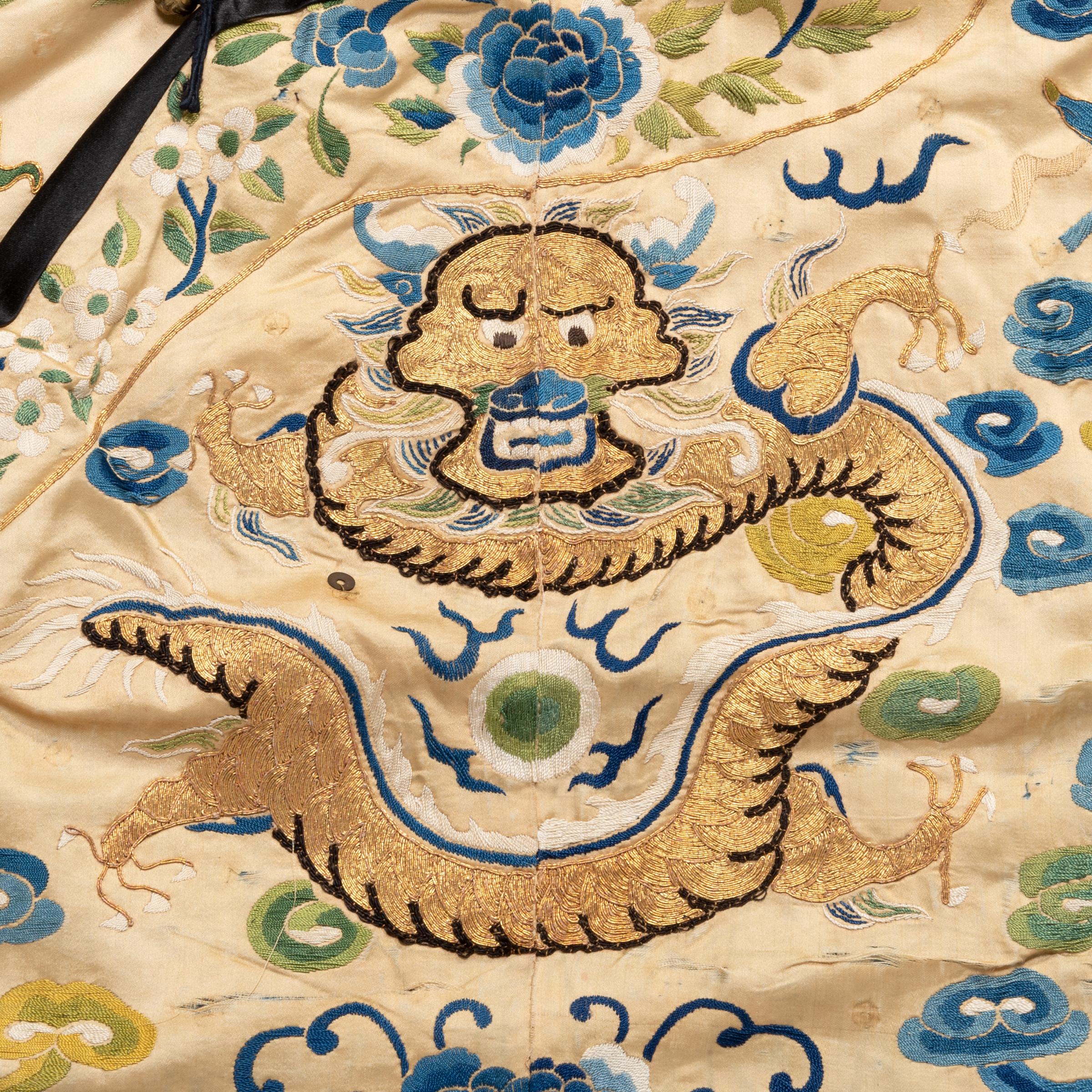 Exquisite Stickereien bilden eine fantastische Kulisse für die mystischen Drachen, die dieses chinesische Gewand aus dem 19. Mit großer Detailtreue und Fantasie dargestellt, wirbeln goldene Drachen über das Kleidungsstück, durch ein himmlisches