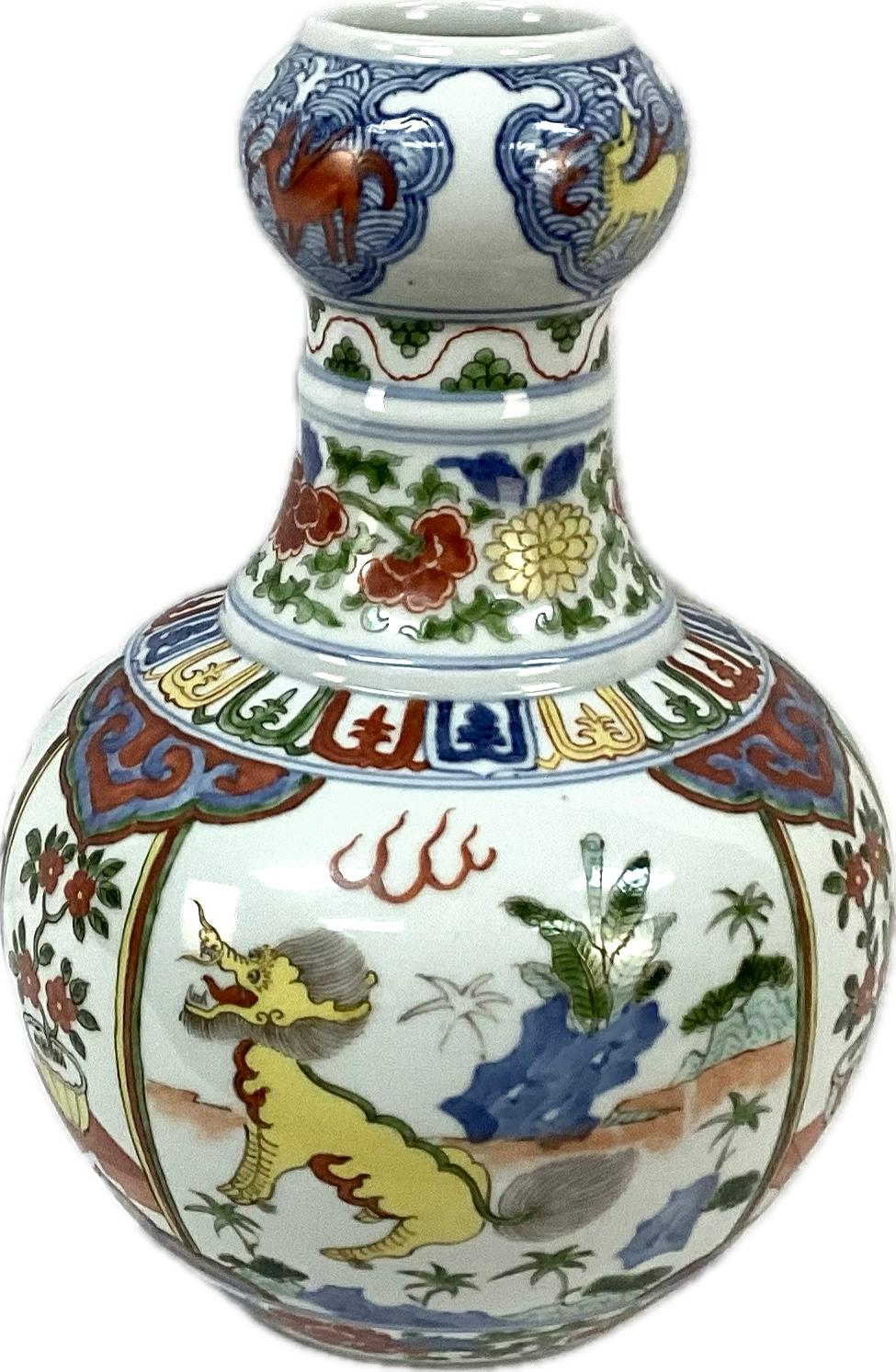  Vase dragon chinois en porcelaine en forme de gourde aux riches couleurs de rouge, bleu, vert et jaune sur fond blanc. Les dragons multicolores sont accompagnés d'une flore et de fleurs. Marques chinoises sur le fond. En très bon état.