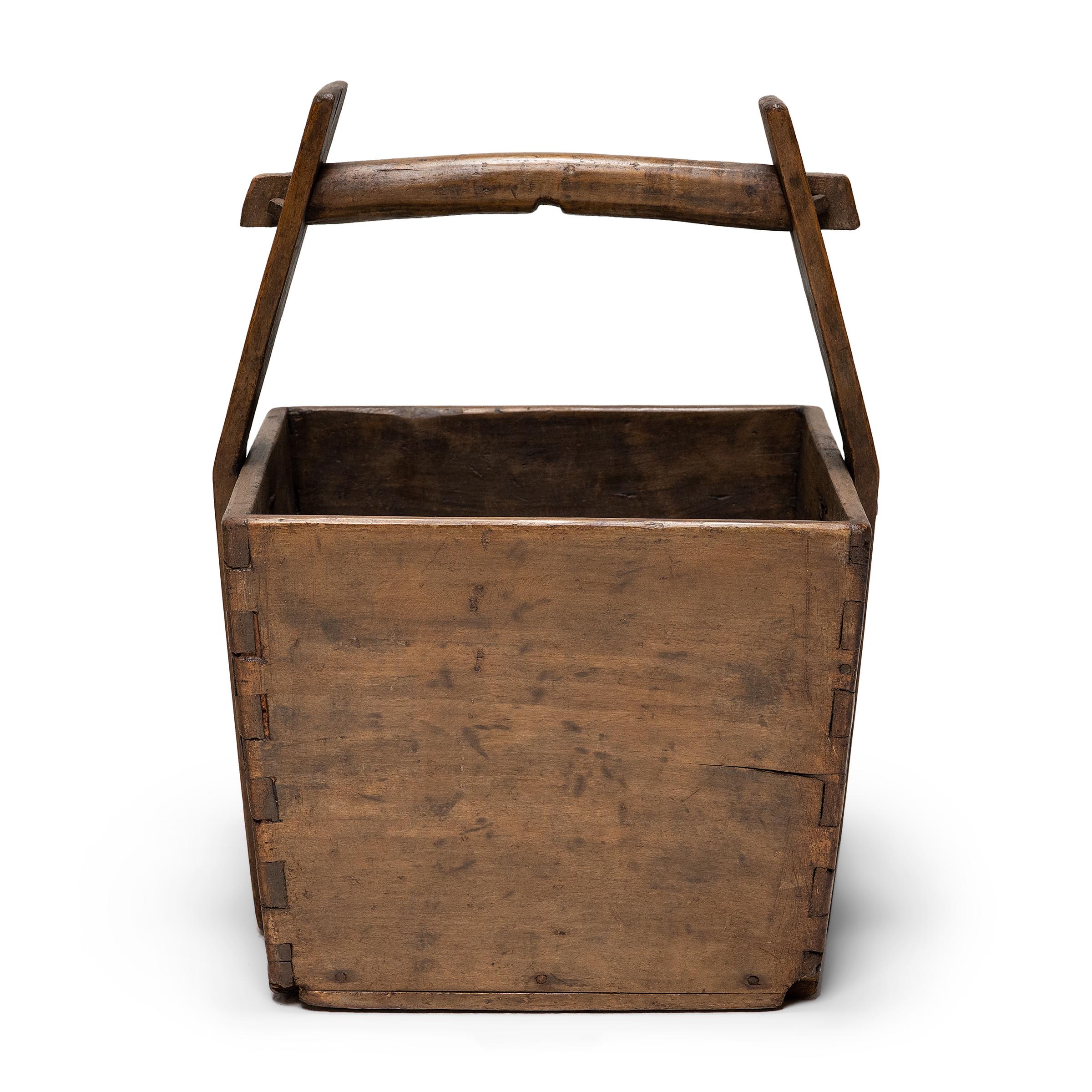 This hand-crafted wooden bucket was once used by farmers in Shanxi, China to transport their harvest of rice and grains over long distances. Counterbalanced by a second container, the pail would have been lifted by a pole threaded through the tall