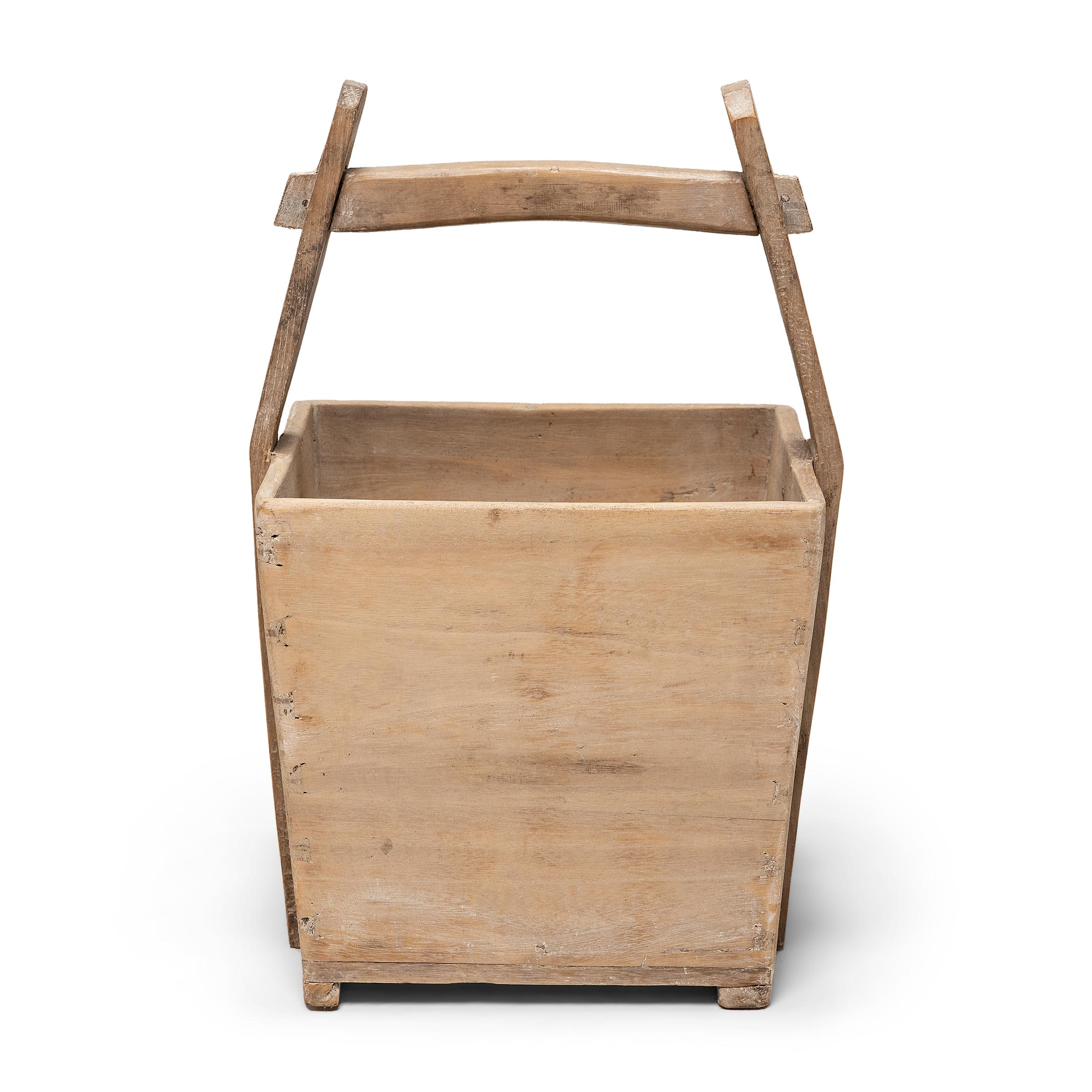 This hand-crafted wooden bucket was once used by farmers in Shanxi, China to transport their harvest of rice and grains over long distances. Counterbalanced by a second container, the pail would have been lifted by a pole threaded through the tall