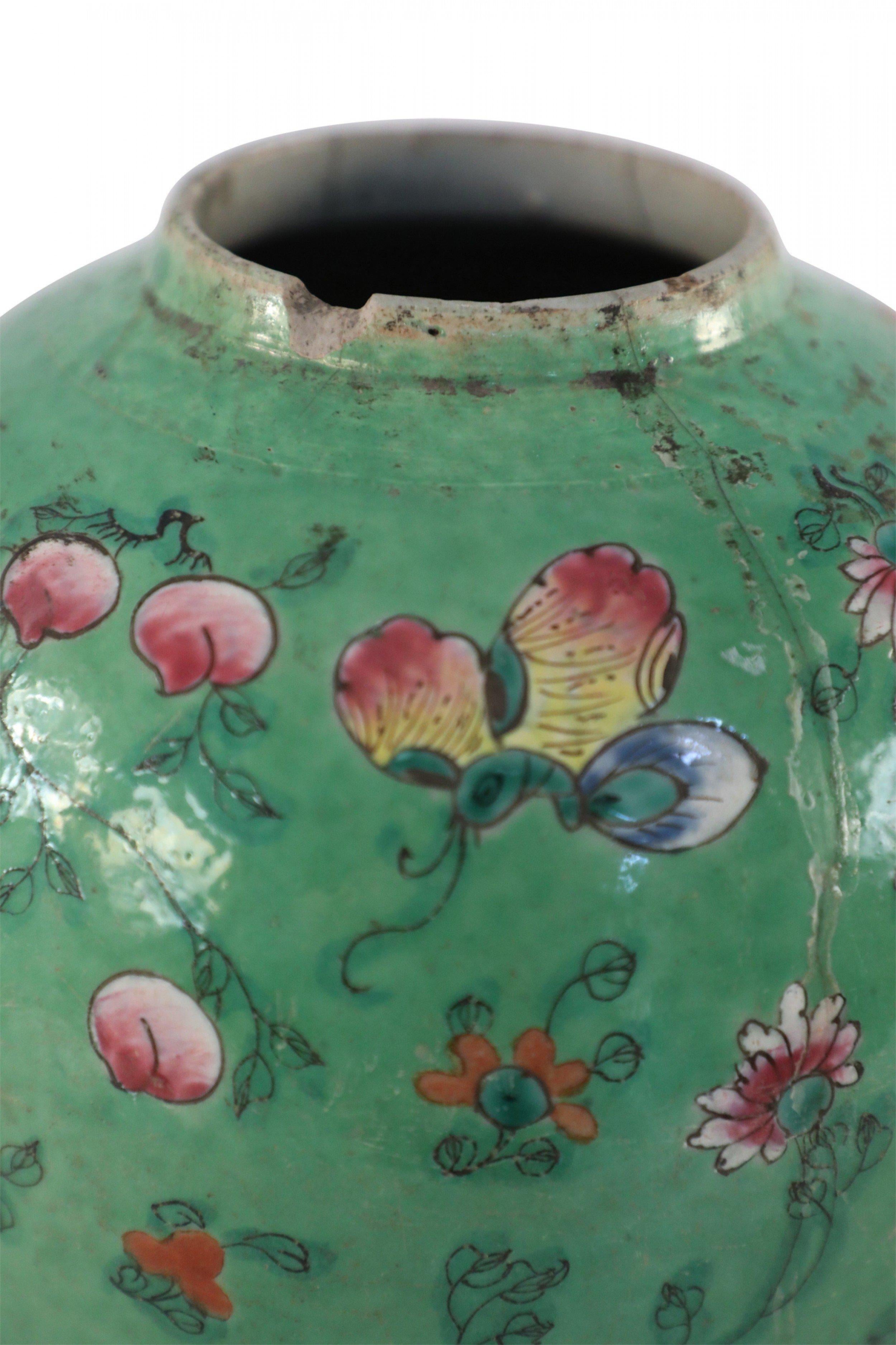 Antique Chinese (Early 20th Century) green porcelain vase with a round form, known as a watermelon jar, incised and painted with delicate, spaced florals in pink, red, yellow, and green tones, and made with a hole in the base.
  