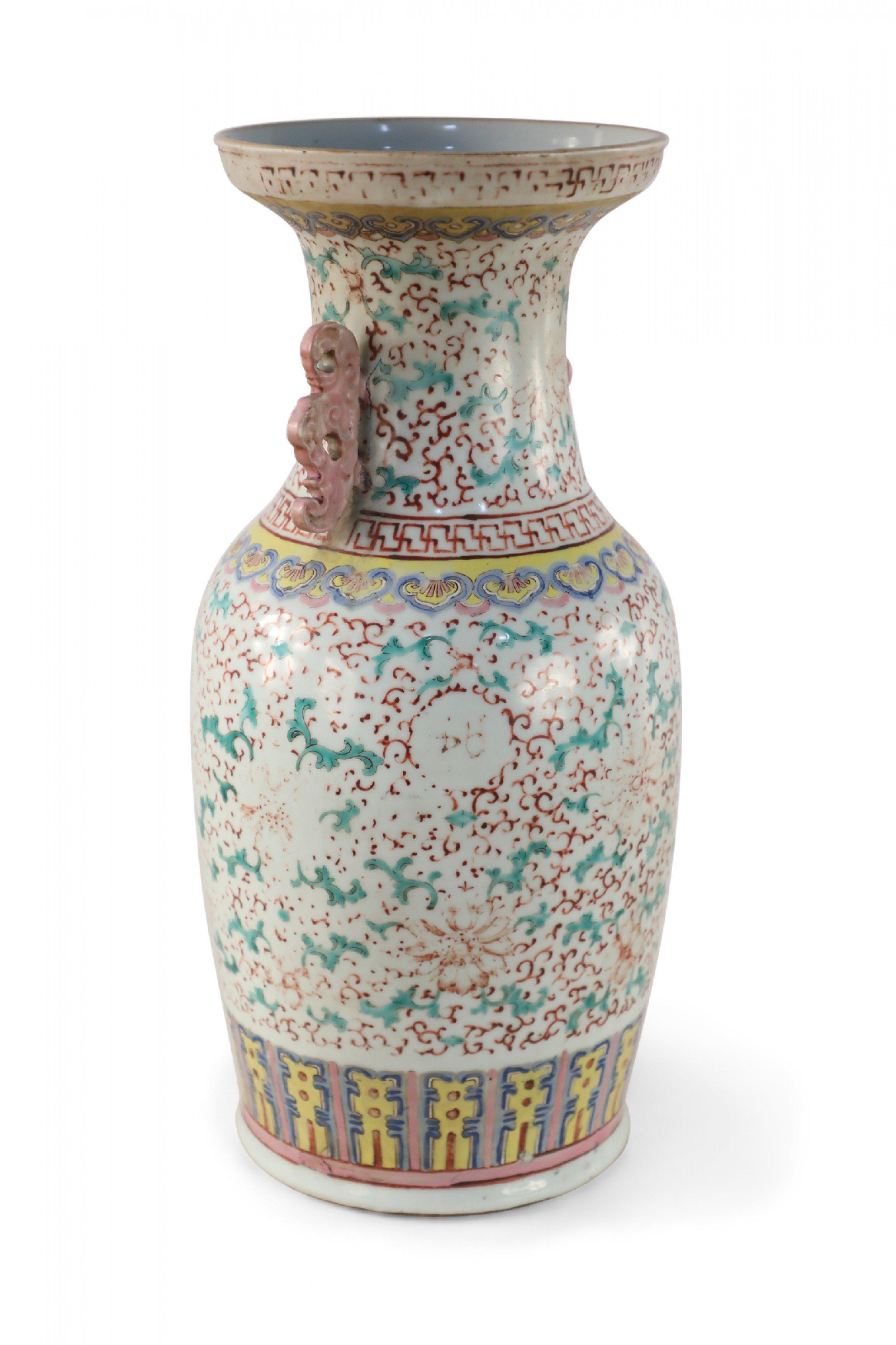 Ancienne urne chinoise (fin du XIXe siècle) en porcelaine blanche décorée d'un motif floral vert et rouge délavé et agrémentée de poignées à volutes rose pâle le long du col.
 