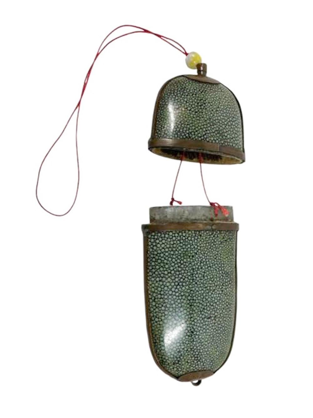 Estuche chino de gafas de papel maché de forma tubular aplanada con extremos cerrados y apertura corredera en el centro cubierto de piel de zapa teñida de verde y ribeteado de cobre. 