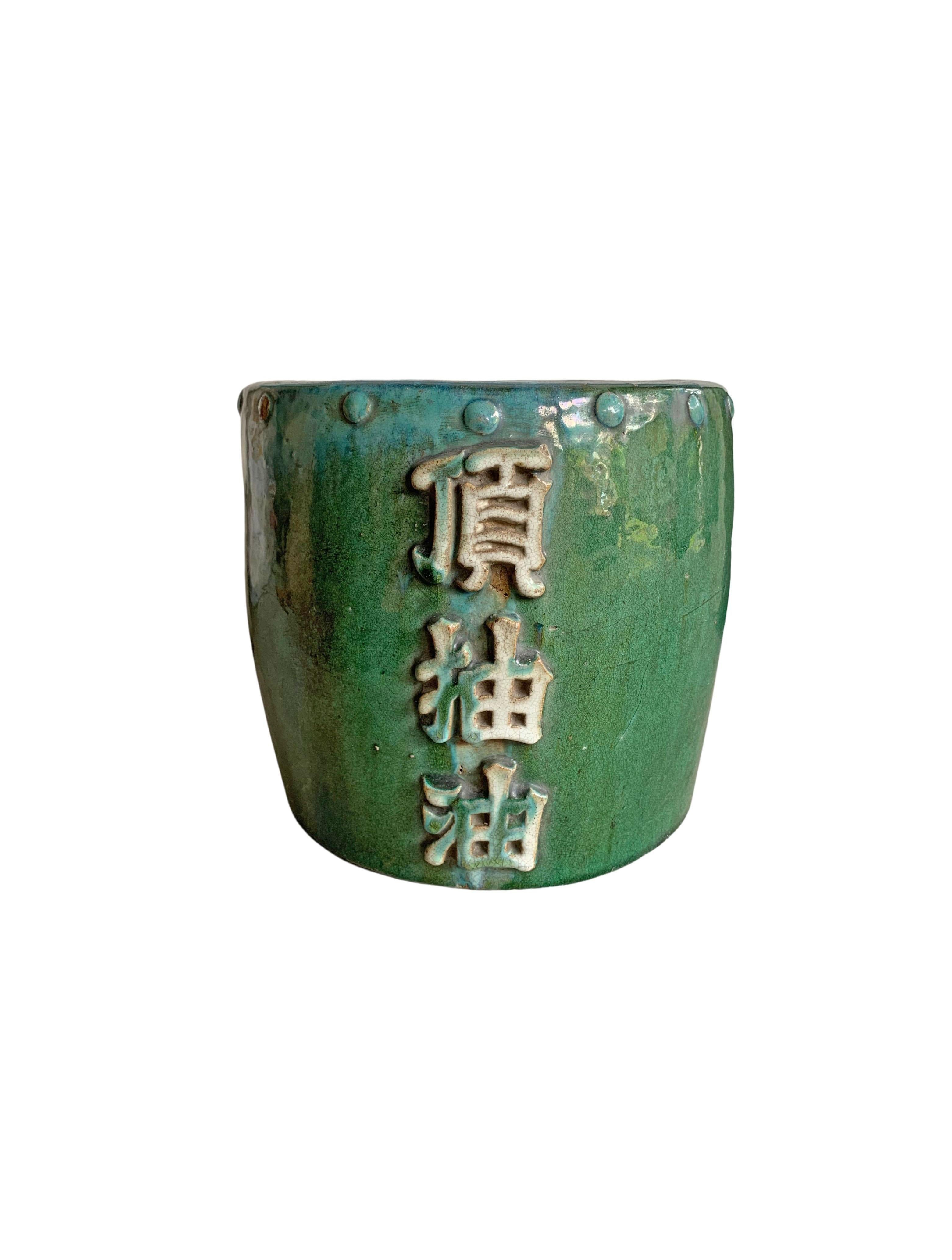 Un meraviglioso smalto verde adorna questo barattolo per olio in ceramica cinese della metà del XX secolo. I caratteri sul lato anteriore si traducono in 