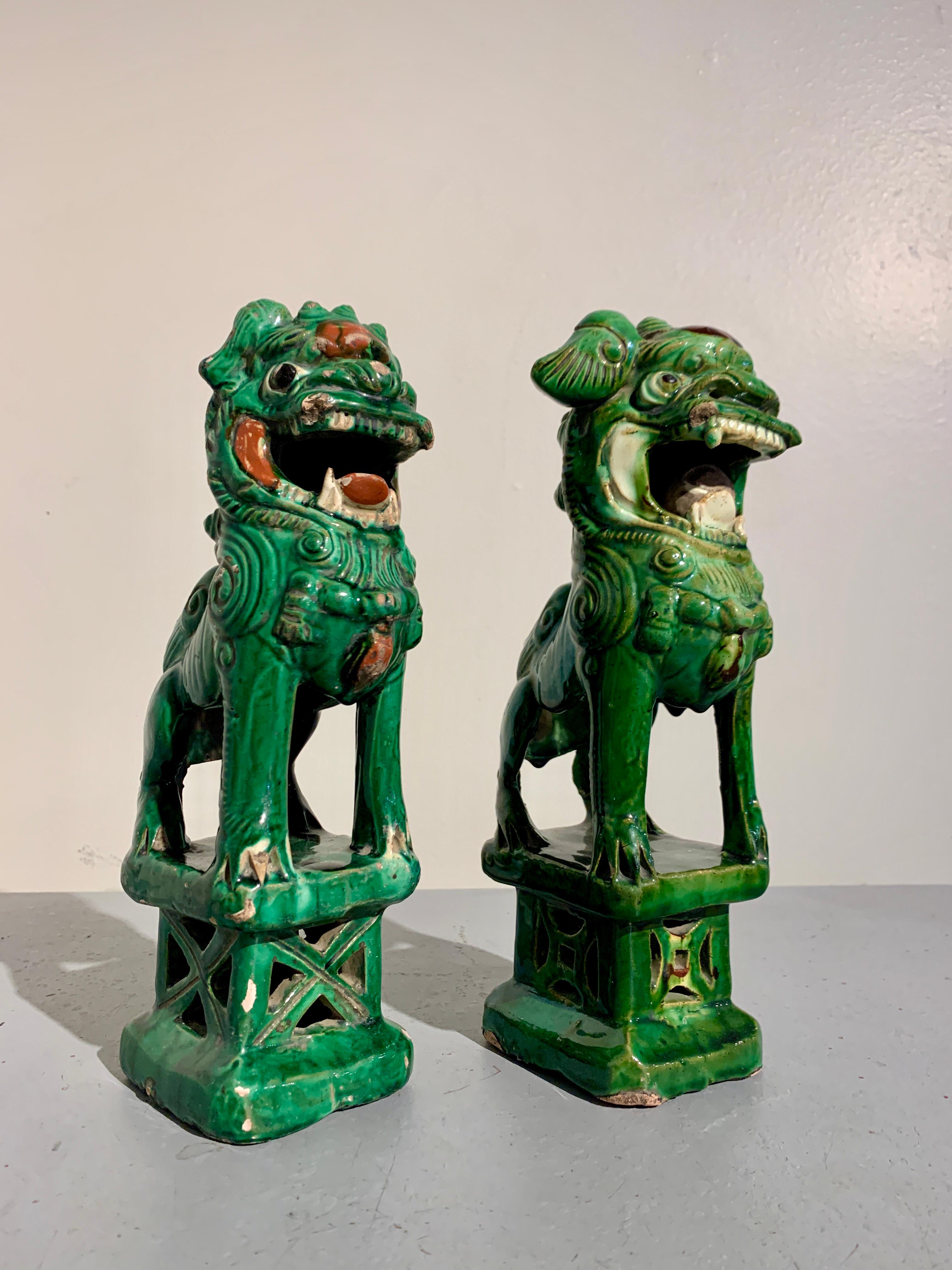 A charming near pair of Chinese green glazed foo lion joss stick holders, late 19th century, China.

The delightful foo lions, also referred to as foo dogs, crafted as joss (incense) stick holders, with a small hole and quatrefoil ash catcher to