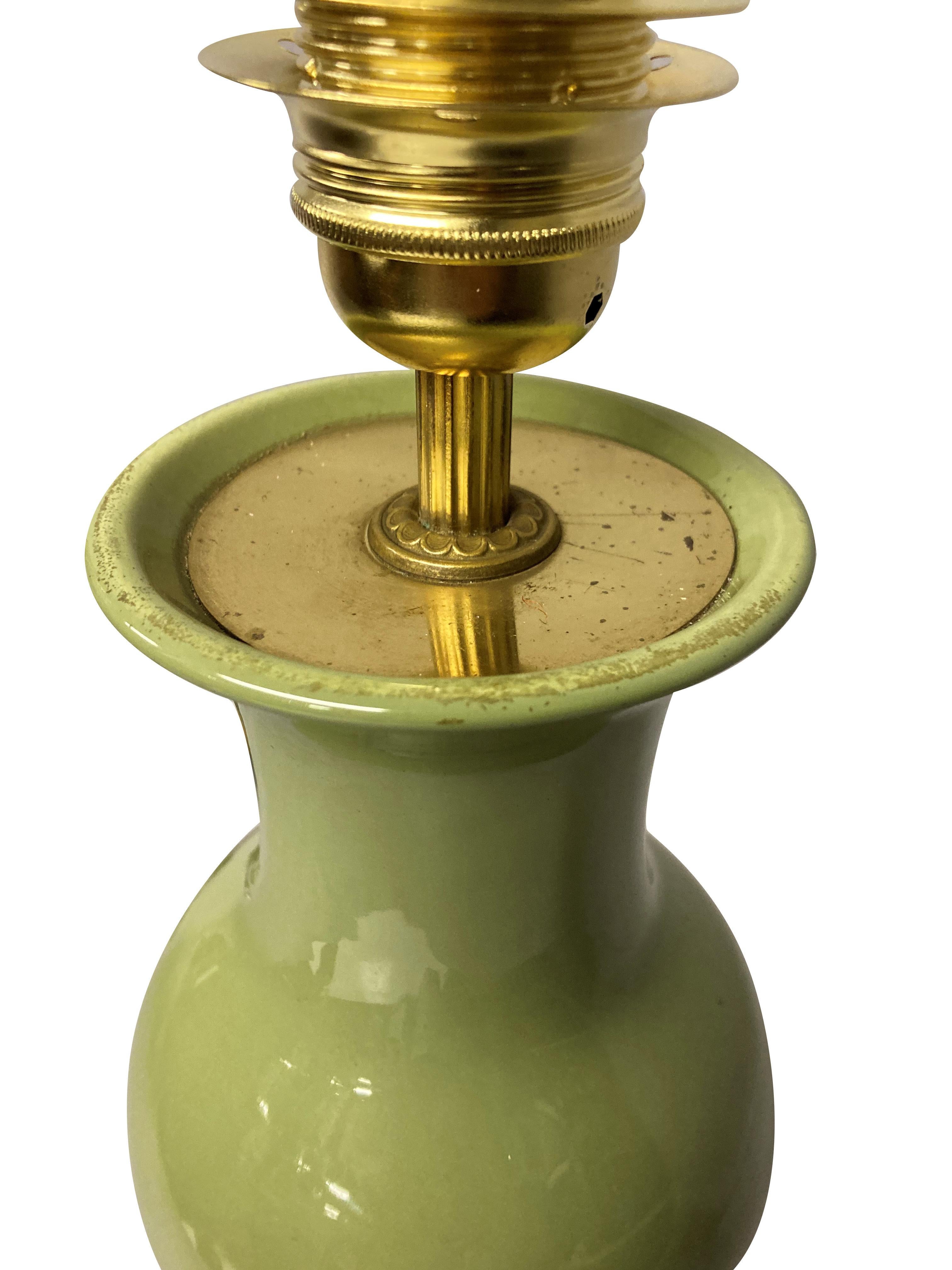 Une lampe chinoise en forme de vase émaillé vert sauge sur une base en bois dur sculpté, avec des accessoires en laiton.