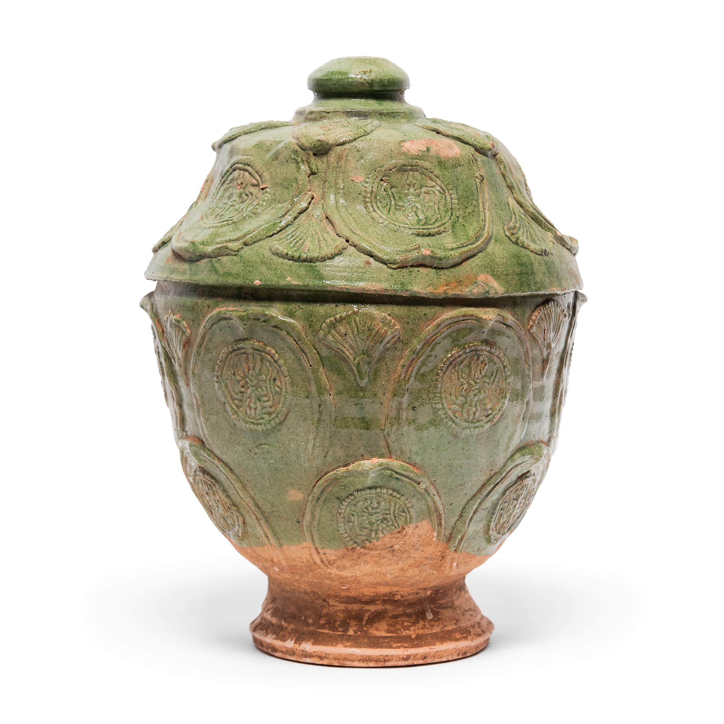 This unusual lidded jar exemplifies the timeless rustic appeal of provincial Chinese pottery. Dated to the late 19th century, the jar has a tapered form and warm green glaze that recalls ancient funerary jars, used for storing food offerings for