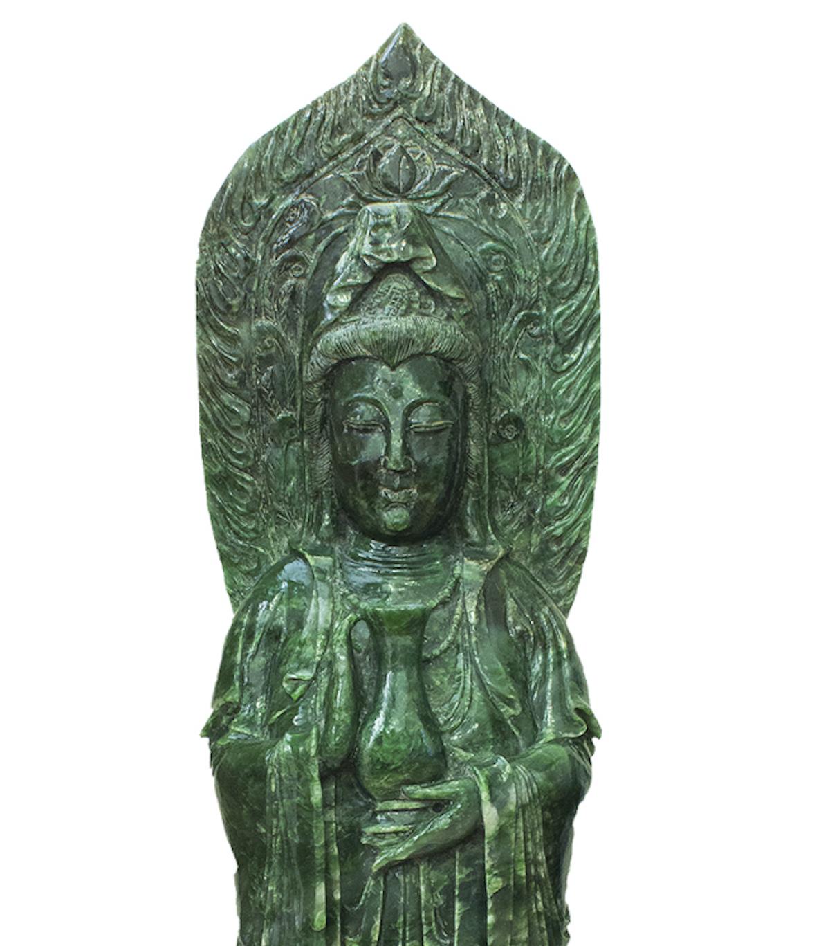 This Chinese green hardstone carving was realized in China during the 20th century. 

This big statue represents a standing Guanyin carrying on the left hand the kundika bottle, beyond his shoulder there is a large halo.

In excellent