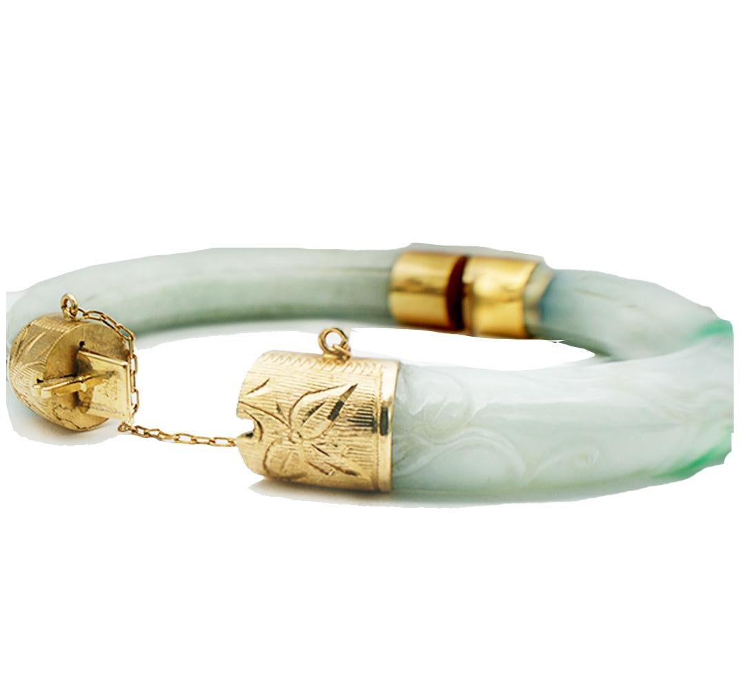 Chinese, Green Jade Bangle Bracelet, 14 karat

55.60 grams of weight.
Sturdy and wide gold caps are on all four ends of the jade giving a safe closure for wear. There is etching on these caps
 Comes with a 14 karat yellow gold safety chain. The