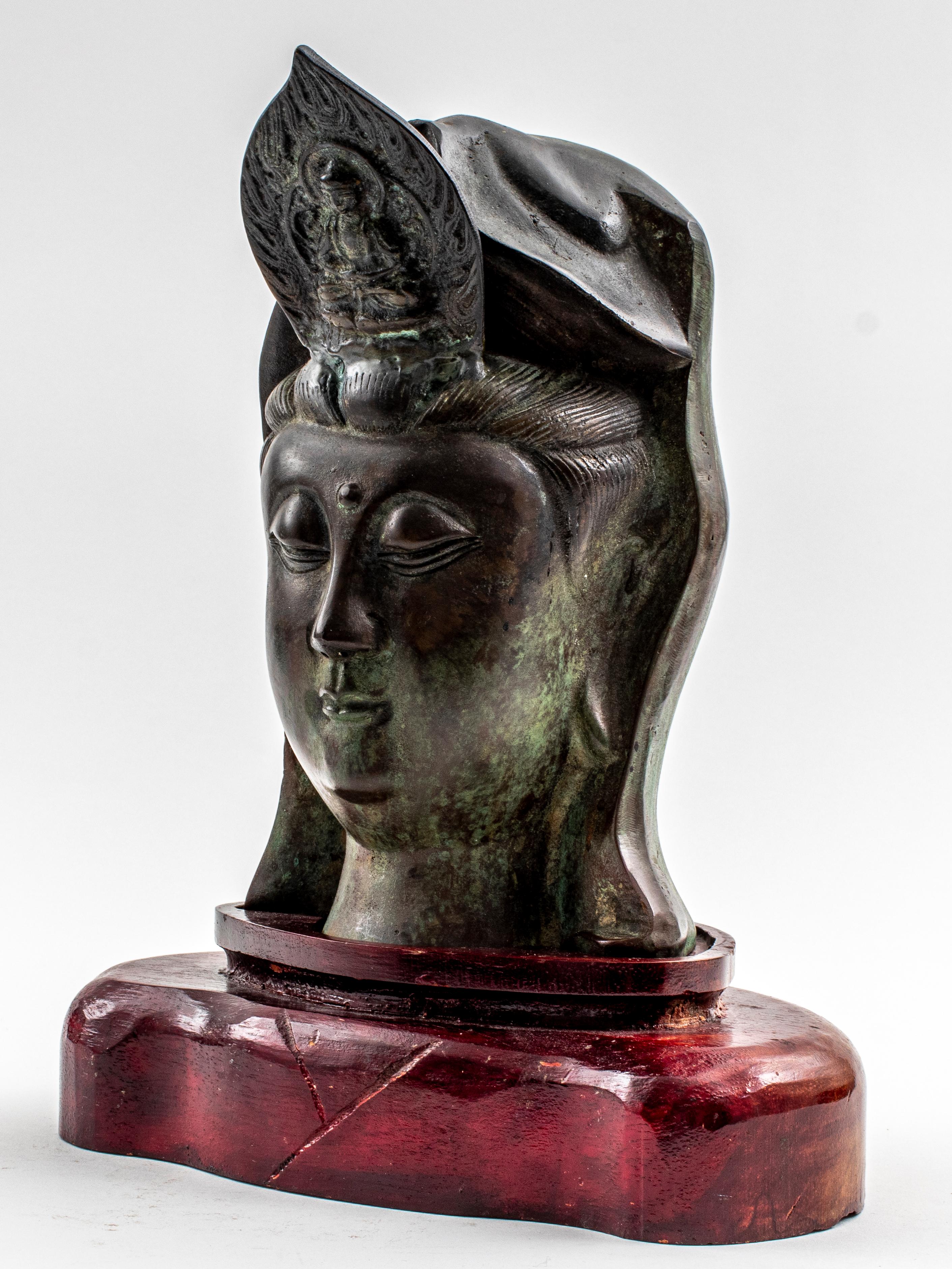 Chinese Guanyin Bodhisattva bronze sculpture, depicting a female head with a crown containing the imagery of the Buddha Amitabha, on wooden stand. 
Measures: 9
