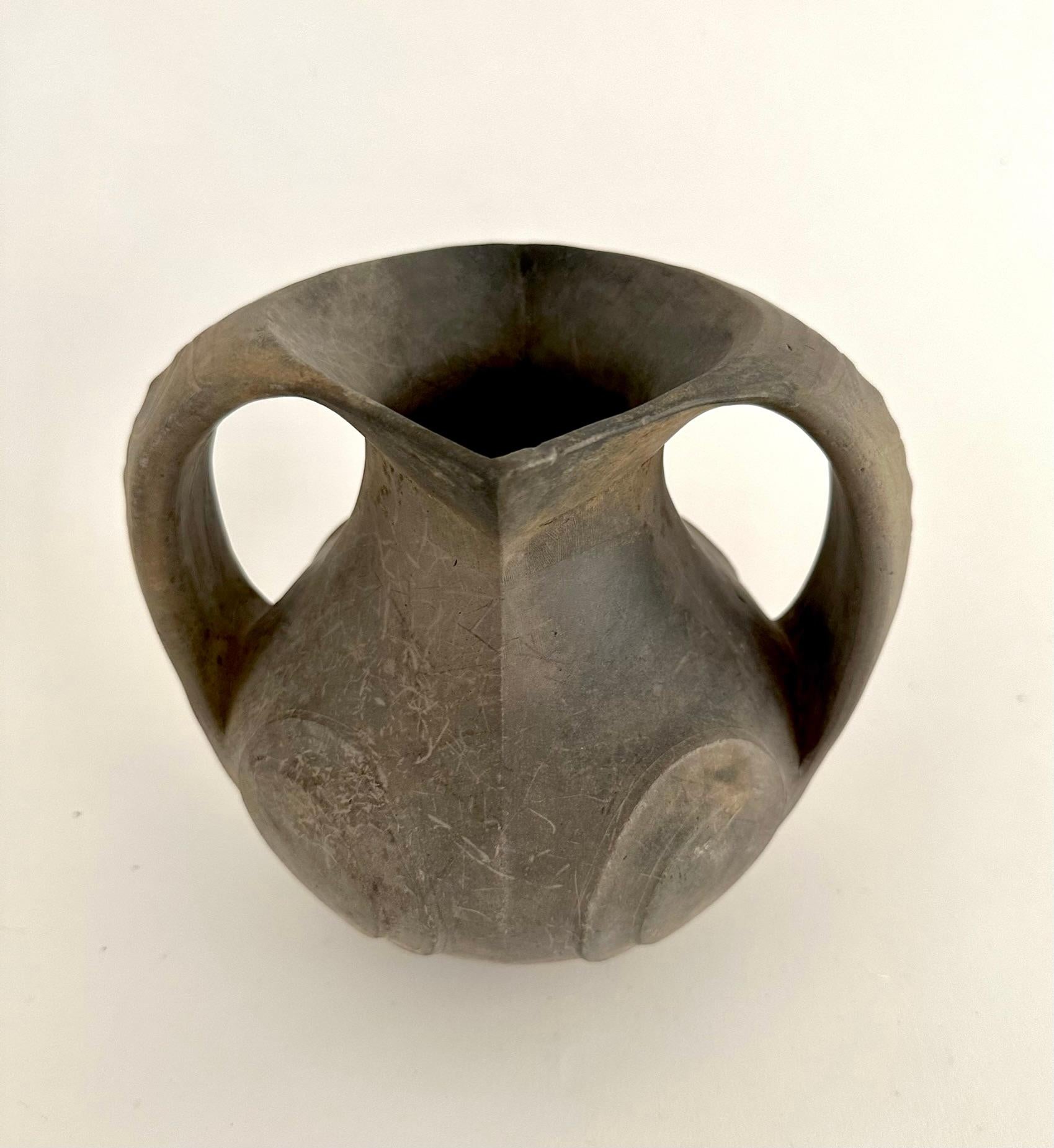 This amphora pot was made some 2,000 years ago during the Han Dynasty (206 BC - AD 220).  This vase is pear form with a vertically incised band around the neck beneath a lozenge-shaped opening at the mouth and the two loop handles, each finished