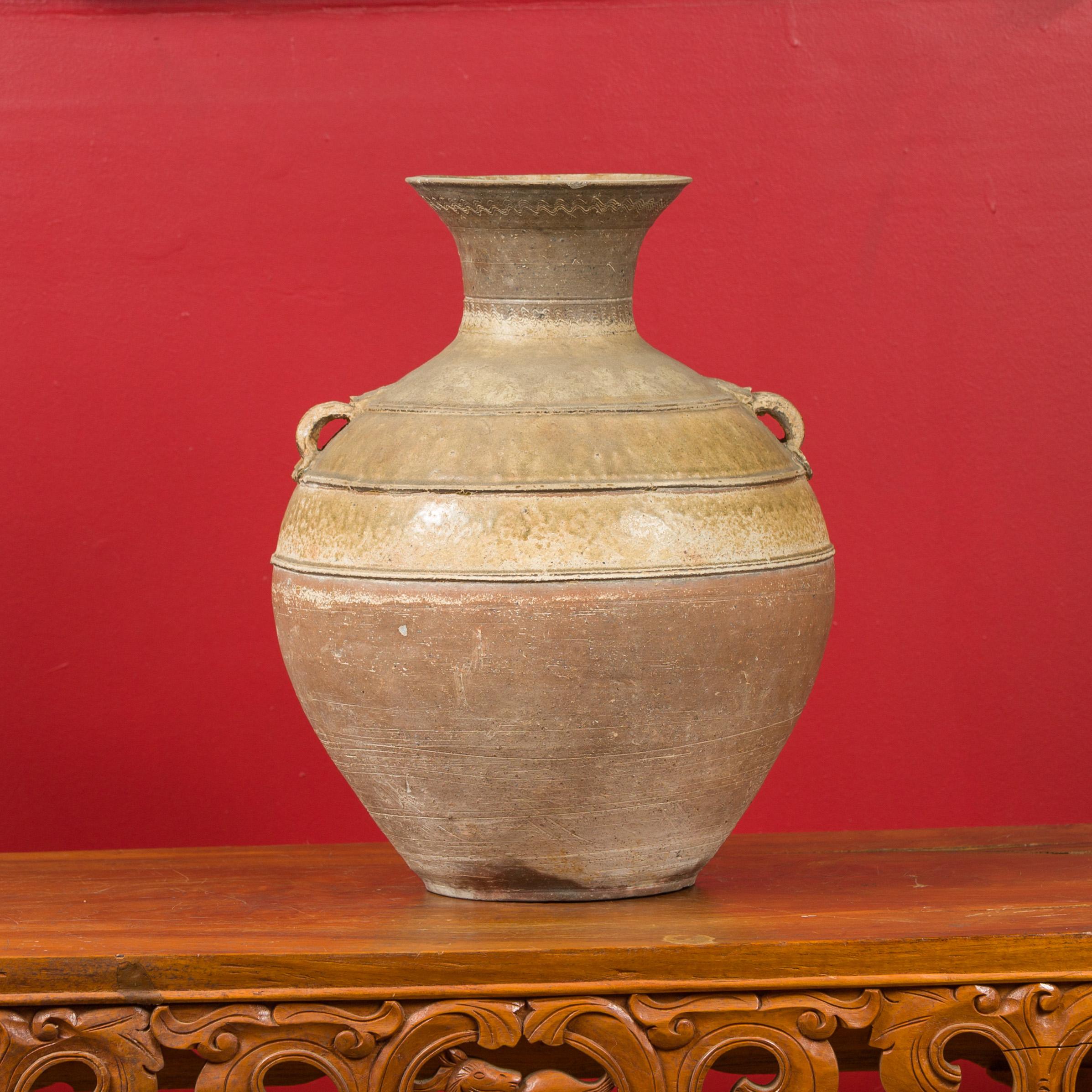 A Chinese Han dynasty period glazed ceramic Hu vessel circa 202 BC-200 AD, with petite decorative handles and wavy motifs. Crafted in China during the Han dynasty, this wine vessel, called a Hu vessel, features a circular belly topped with a narrow