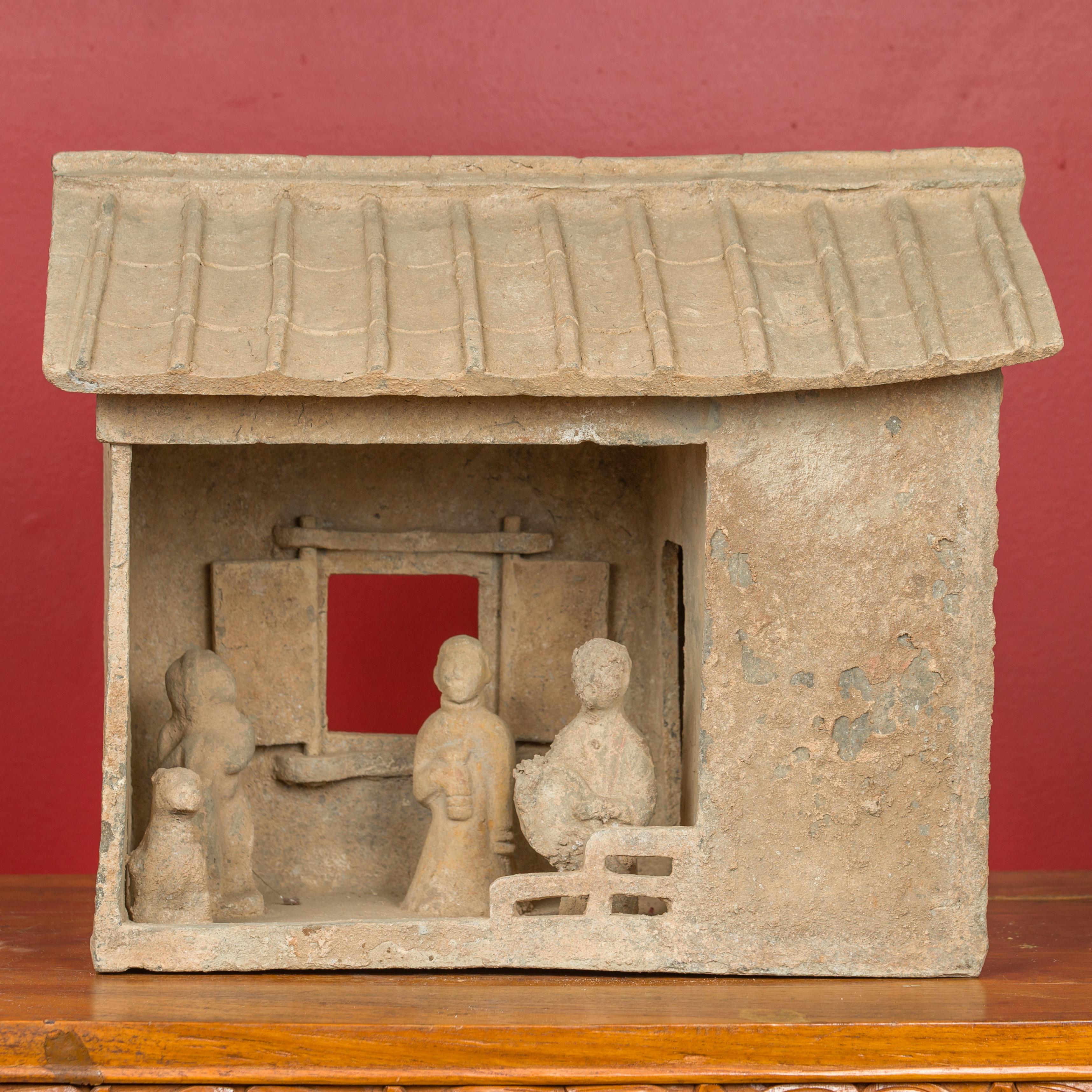 A Chinese Han Dynasty farm house model with its occupants and removable roof circa 206 BC-AD 221. Crafted during the Han Dynasty, this mingqi house model features a slanted roof (removable), sitting above an open room presenting a door leading to a