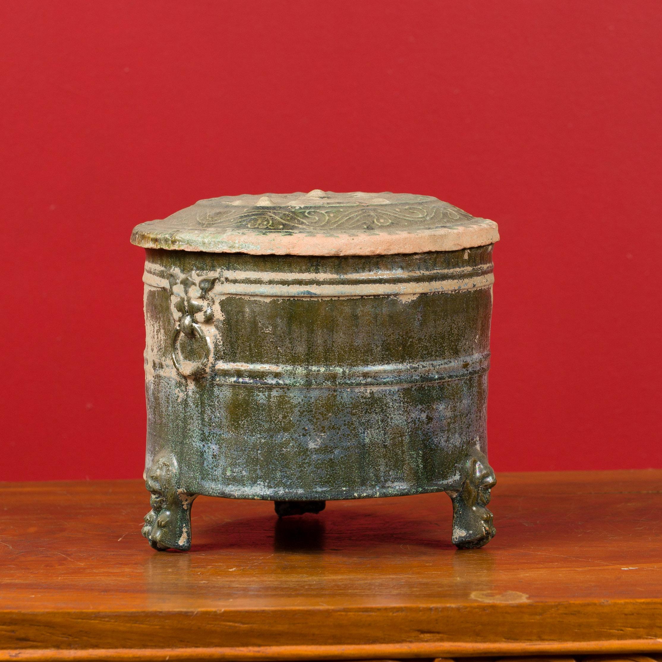 A Chinese Han Dynasty period glazed terracotta lidded vessel, circa 202 BC-200 AD. Created in China during the prestigious Han dynasty, this small vessel features a circular lid adorned with radiating and scrolling motifs. Resting on three petite