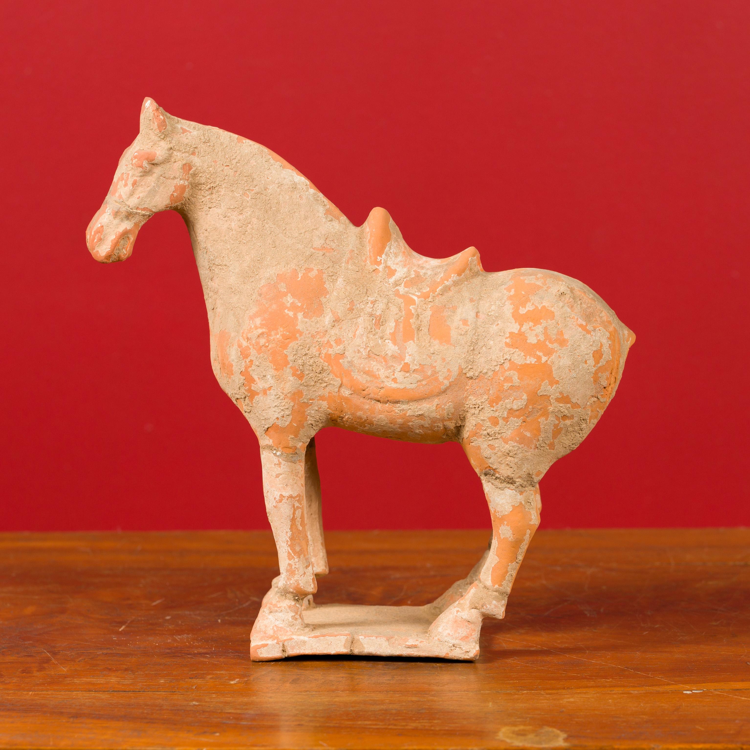 A Chinese Han dynasty period mingqi terracotta horse with traces of original paint, circa 202 BC-200 AD. This mingqi, a funerary statue created to be buried with the deceased to secure an enjoyable afterlife, features a horse proudly standing on its