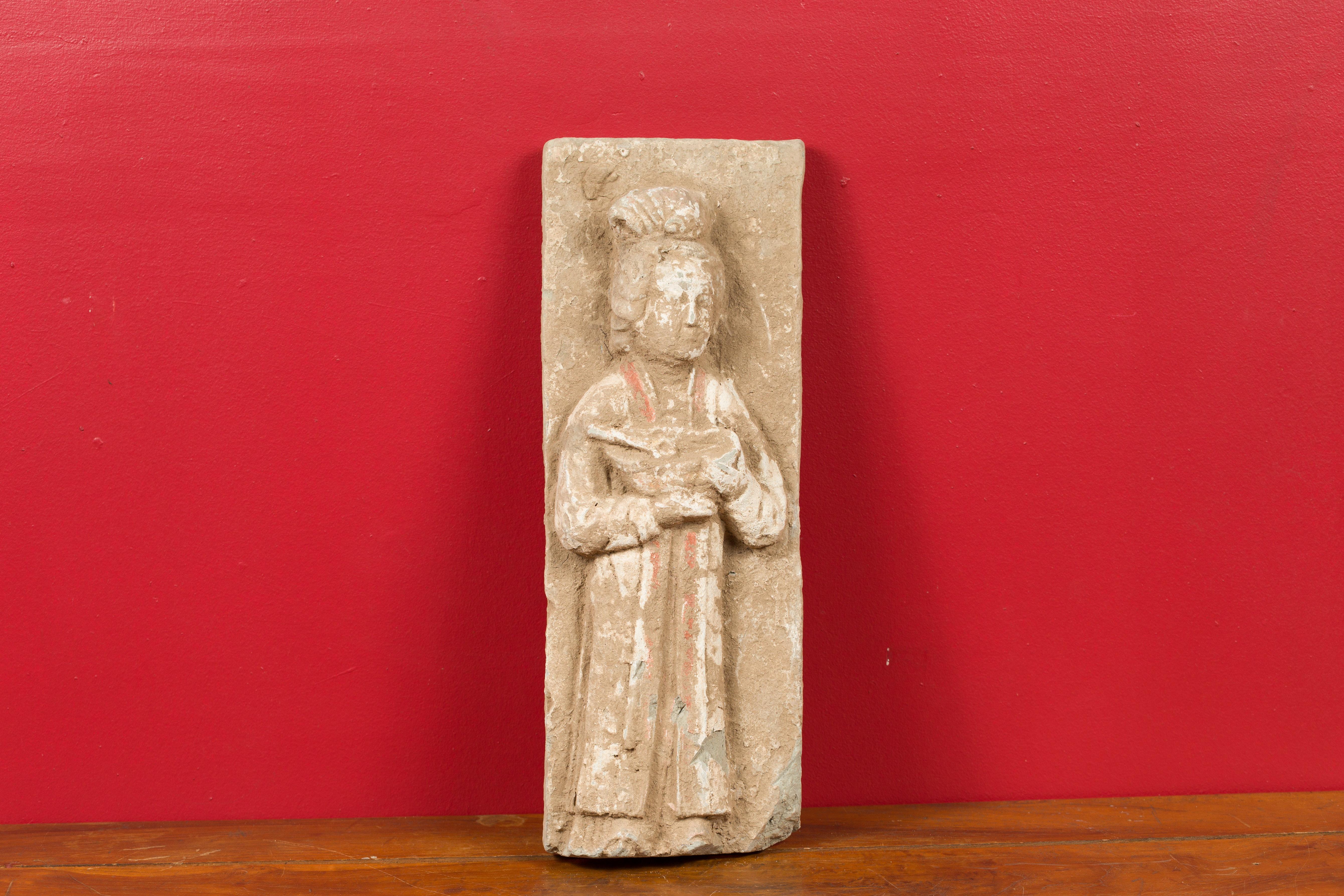 A Chinese Han Dynasty wall plaque depicting a woman carrying a dish, circa 202 BC-200 AD. Created in China during the prestigious Han Dynasty, this wall plaque attracts our attention with its skillful depiction and nicely weathered appearance