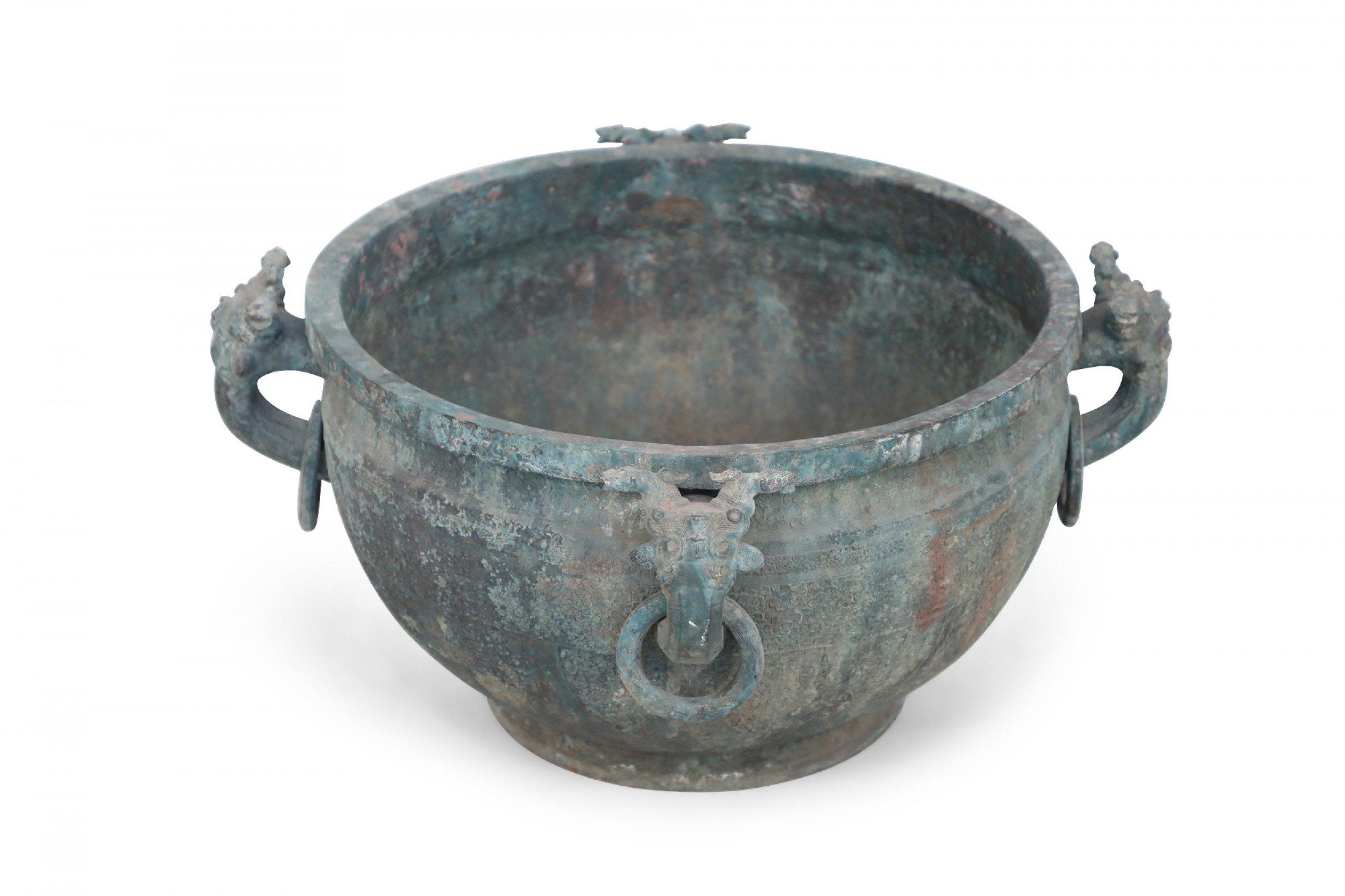 Antigua copia china de estilo dinastía Han de una olla de bronce patinado tallada con motivos geométricos que envuelven su forma y adornada con ornamentos decorativos de aldaba.

Estado: Bueno; Desgaste acorde con la edad y el uso