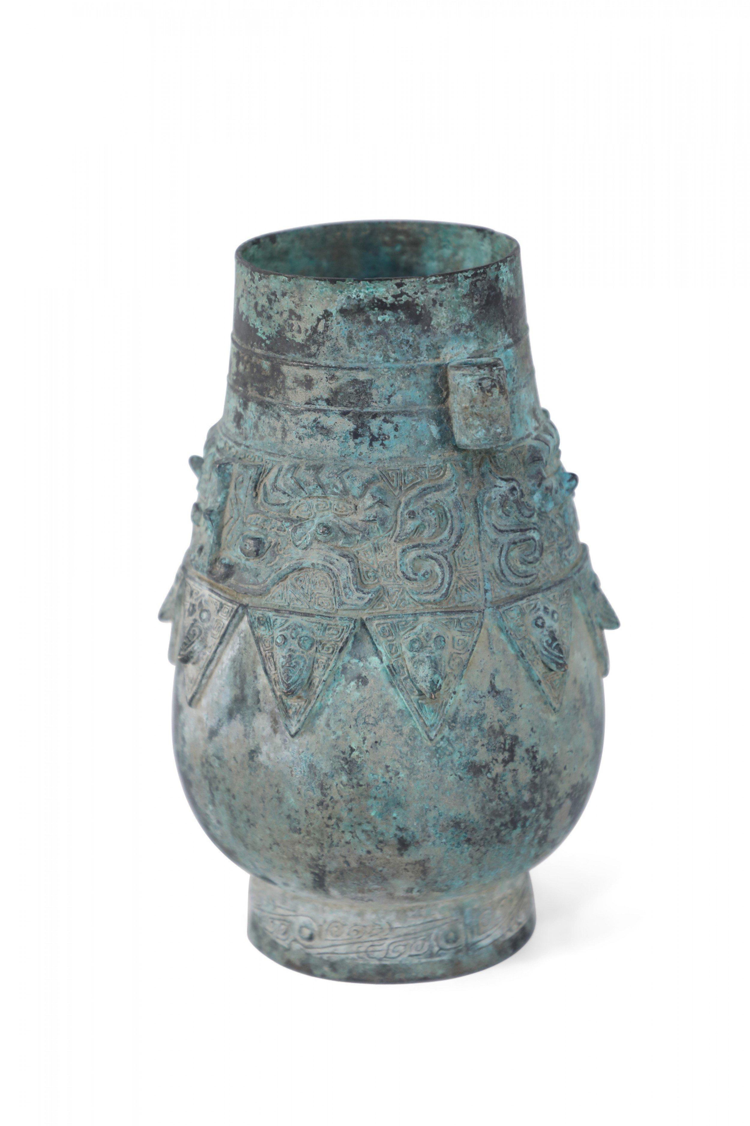 Antica copia in stile Dinastia Han cinese di un vaso in bronzo patinato con un corpo bulboso decorato con bande a motivi geometrici in rilievo, posto in cima a una base circolare e arricchito da due orecchie ad ansa sui lati.
