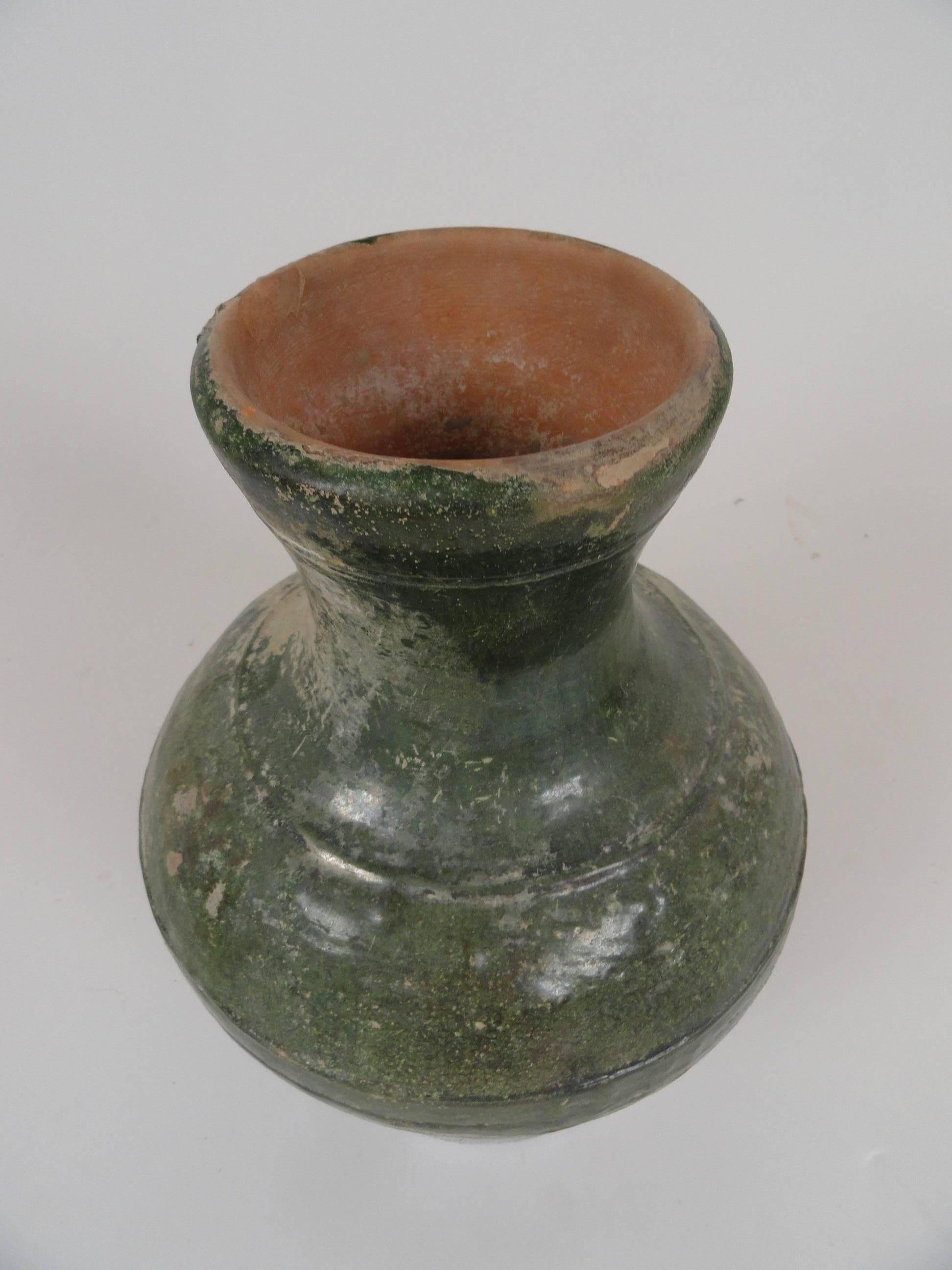 Chinese Han dynasty glazed ceramic urn featuring tones of deep green. Large mouth. Decorative incised bands surrounding the base.