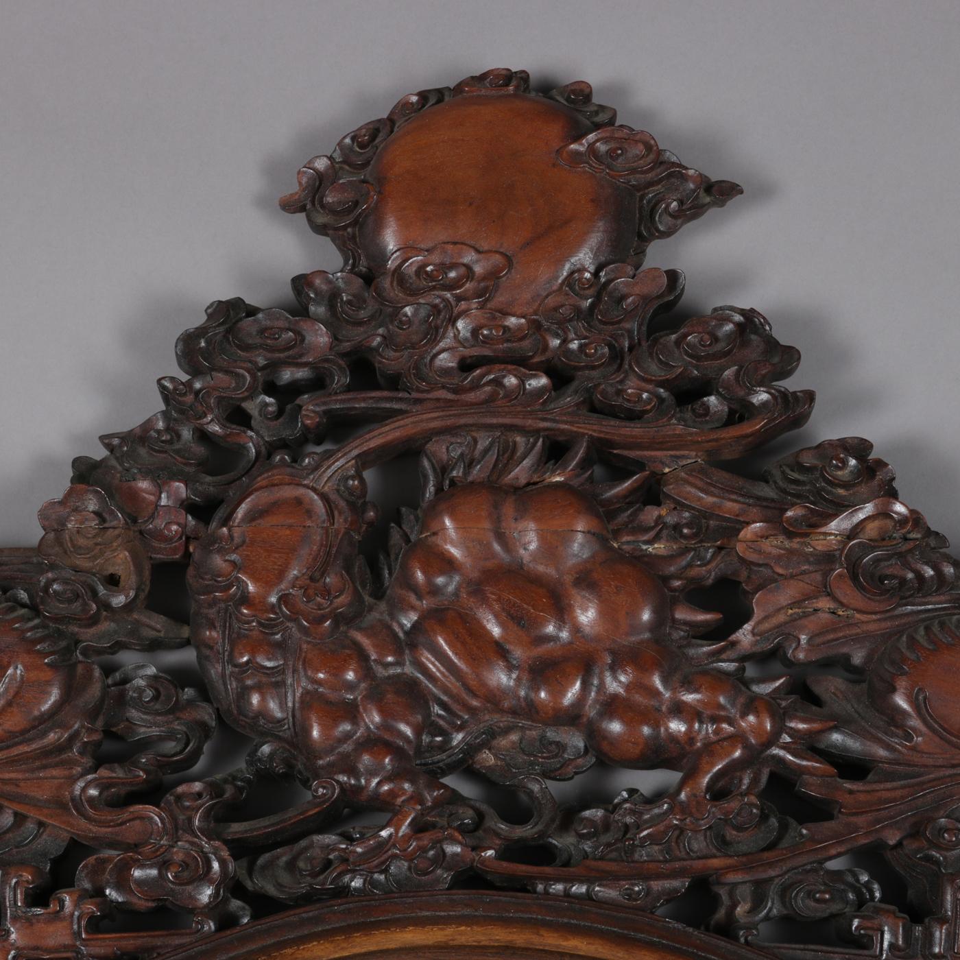 Antique Chinese wall mirror features hand carved hardwood frame with deep foliate form pediment, 20th century

Measures: Overall 35.5
