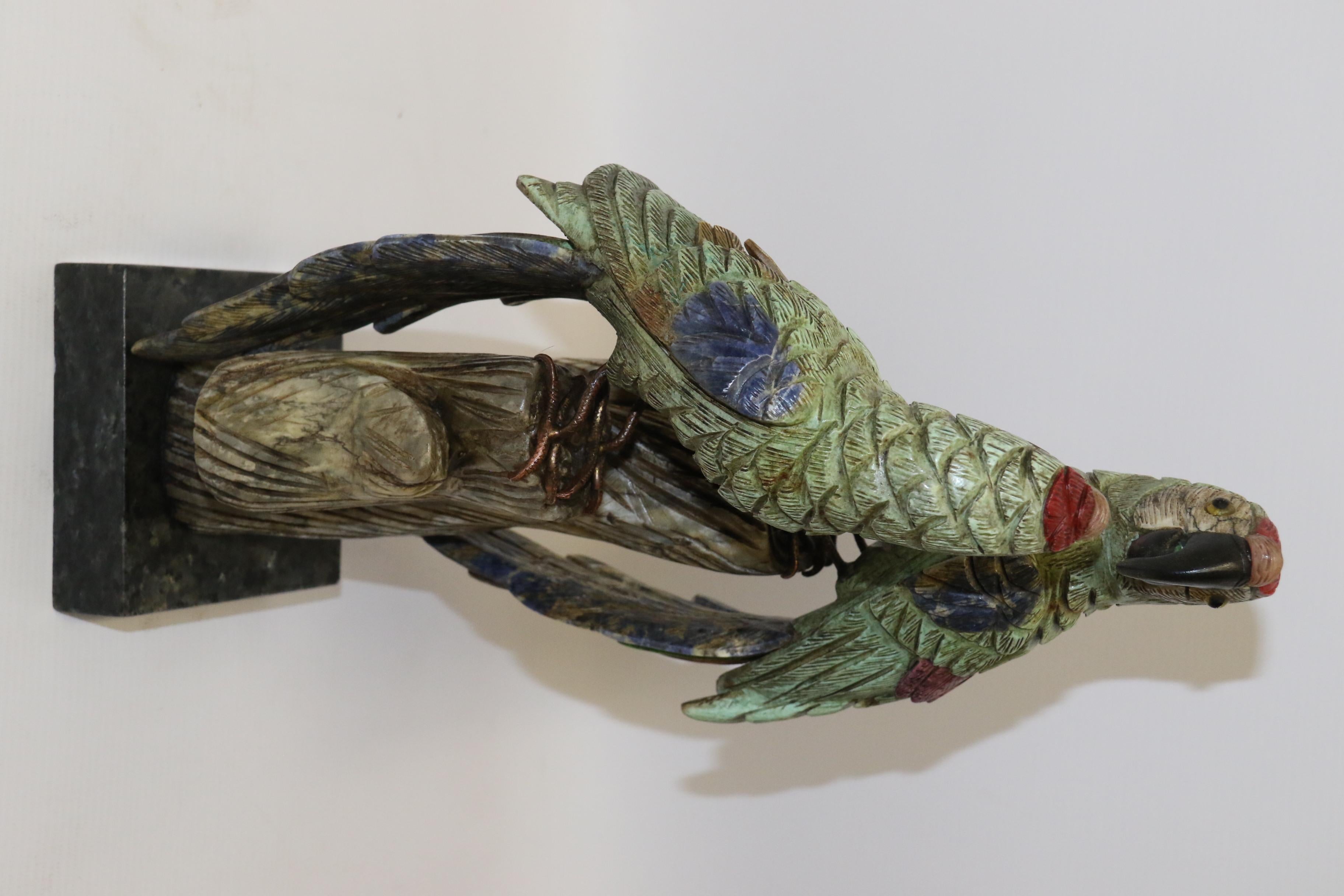 This highly decorative large hand carved sculpture of a pair of parrots sitting on a log whilst looking at each other is most unusual. It is carved from multiple pieces of different colored soapstones and mother of pearl which have been creatively