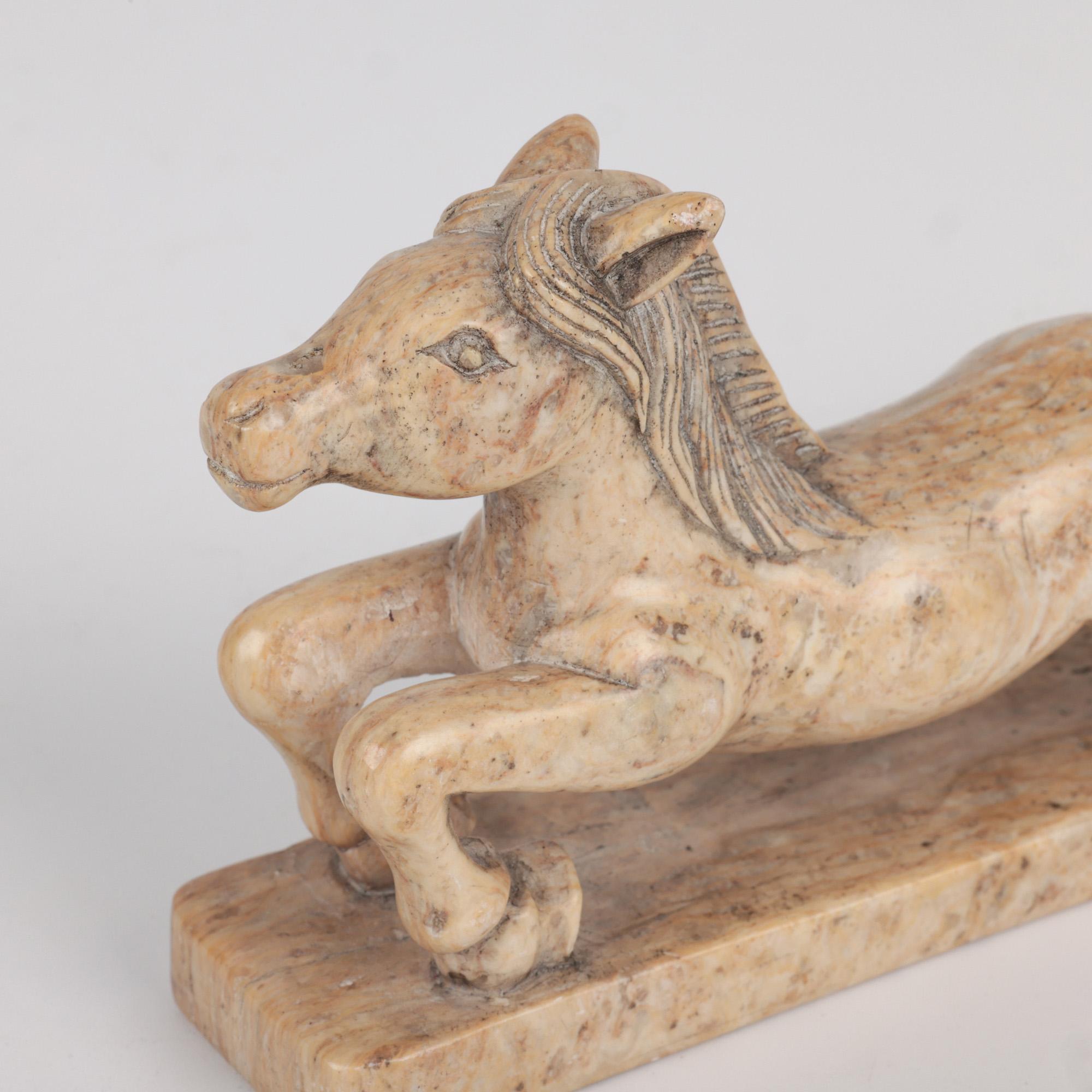 A very fine Chinese hand carved soapstone figure of a galloping horse dating from the early to mid 20th century/ The horse is carved on a long integral base and is carved in an extended running form with its rear legs slightly elevated with a raised