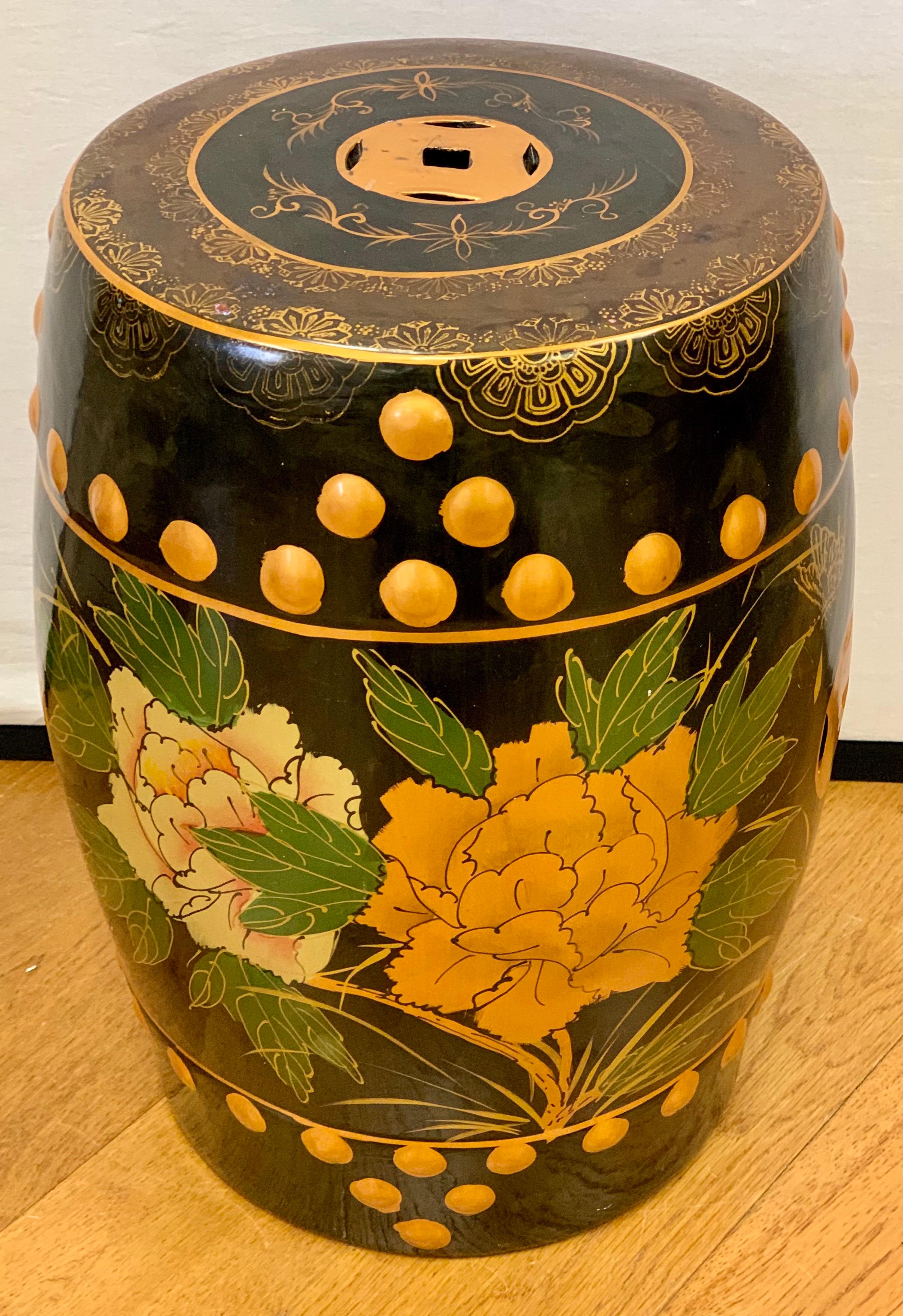 This unique Chinese porcelain garden stool has a black and gold color scheme with hand painted peonies and raised round gold detail all around.