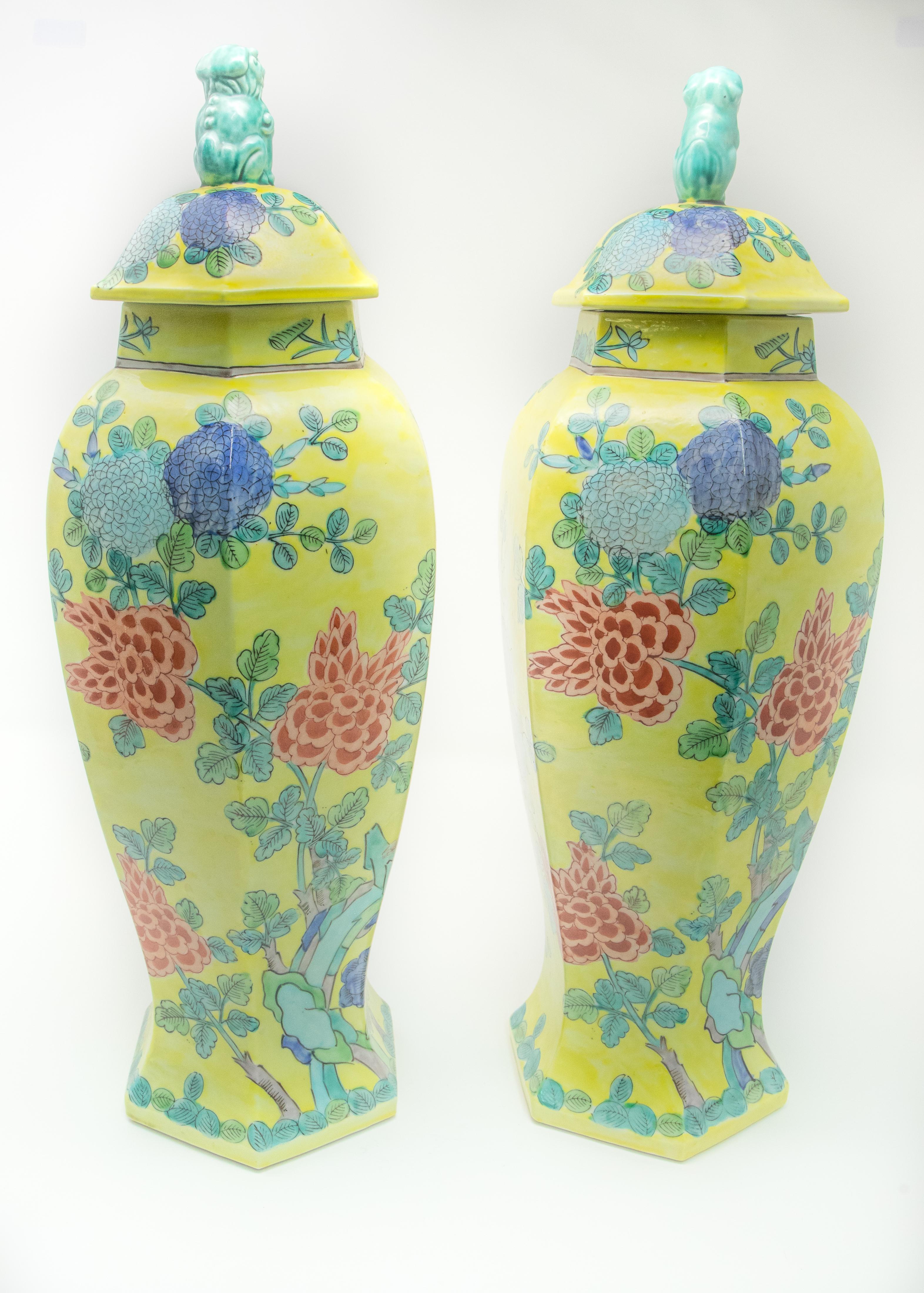 Pair of Chinese hand painted lidded urns. Striking yellow as the base color shows off the shape well. With turquoise, blues, reds, greens, and other wonderful colors making the foliate details. On top of the lids is turquoise painted foo-dogs.