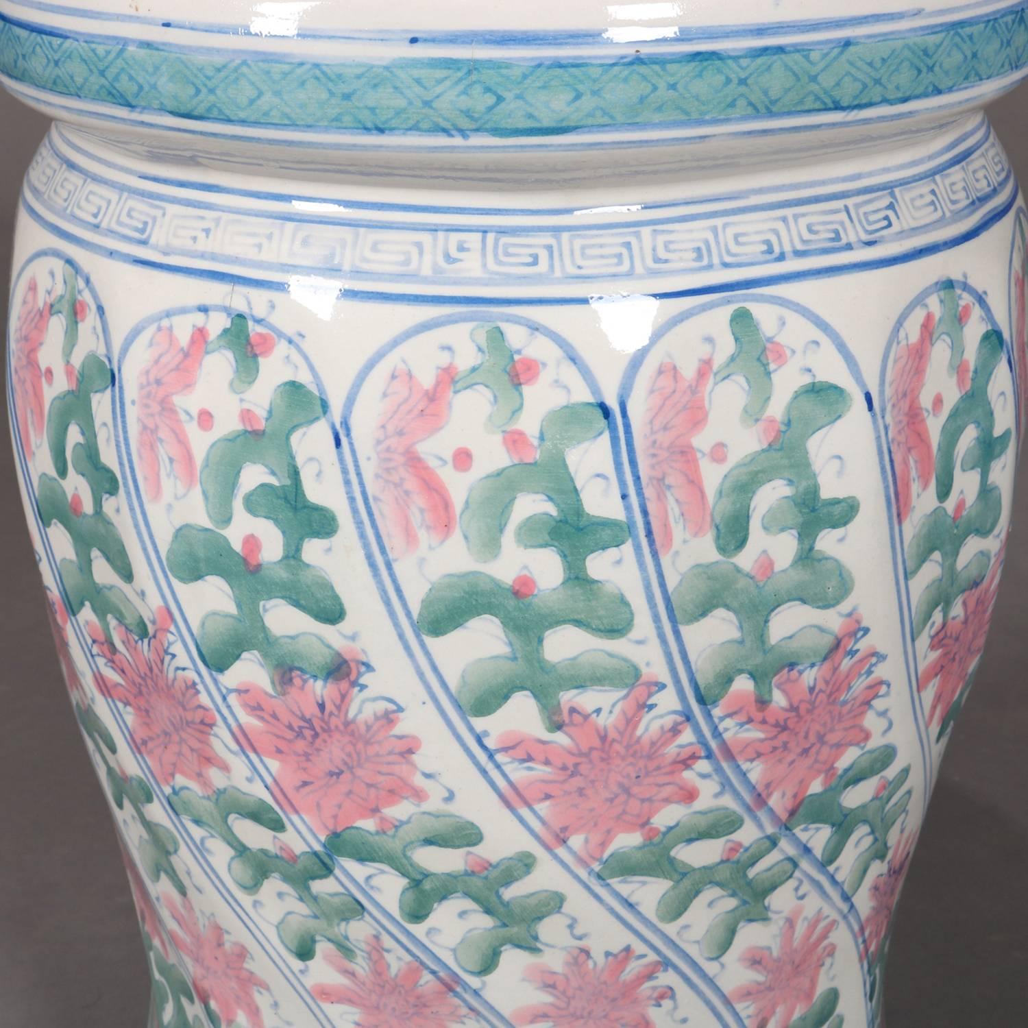 Chinese porcelain garden seat features cylindrical form with hand-painted stylized tobacco leaf design on pierced seat, repeating twisting panels of floral and foliate design, Greek key bordering , pastel palette, 20th century

Measures: 17