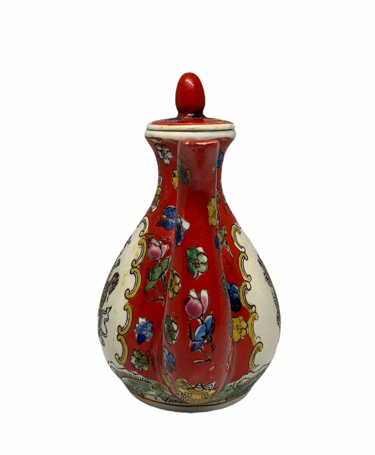 This is a small Chinese hand painted wine pot or teapot depicting a red background with some tiny different colors flowers. In the front and back center there is a scene of a Chinese man riding a 